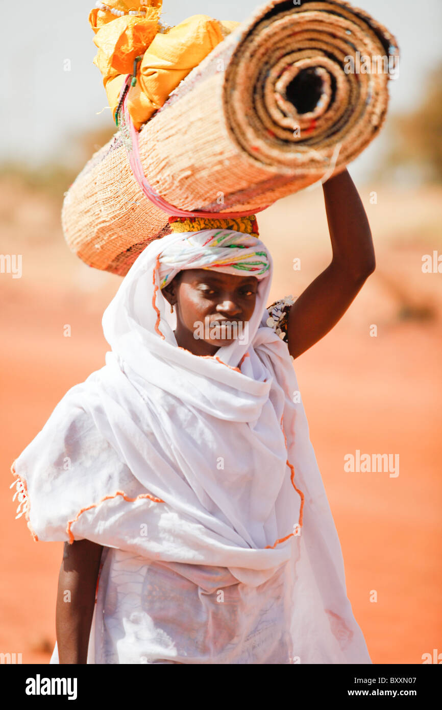 In Djibo in northern Burkina Faso, a Fulani womea brings handwoven straw mats to market for sale. Stock Photo
