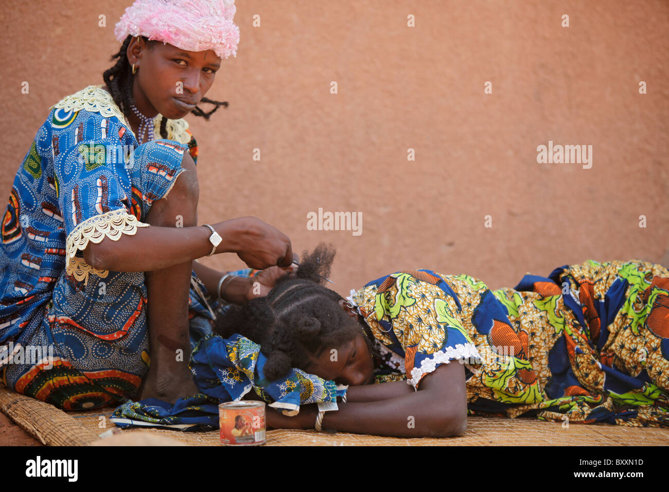 In the town of Djibo in northern Burkina Faso, a young woman braids her cousin's hair in traditional Fulani style. Stock Photo