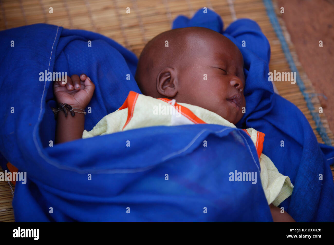 A baby sleeps on a straw mat on the ground in Djibo in northern Burkina Faso. Stock Photo