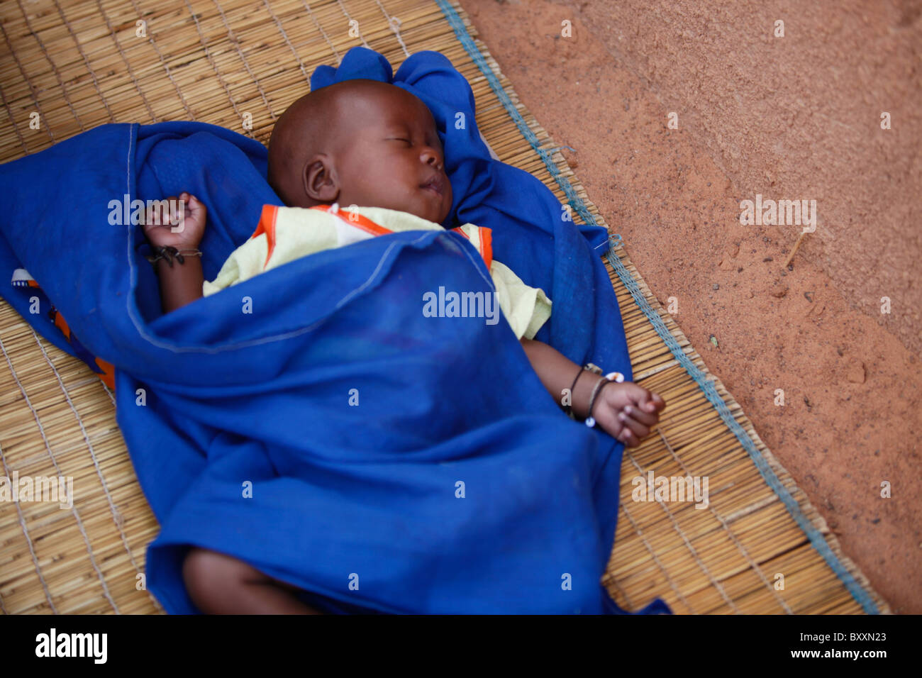 A baby sleeps on a straw mat on the ground in Djibo in northern Burkina Faso. Stock Photo