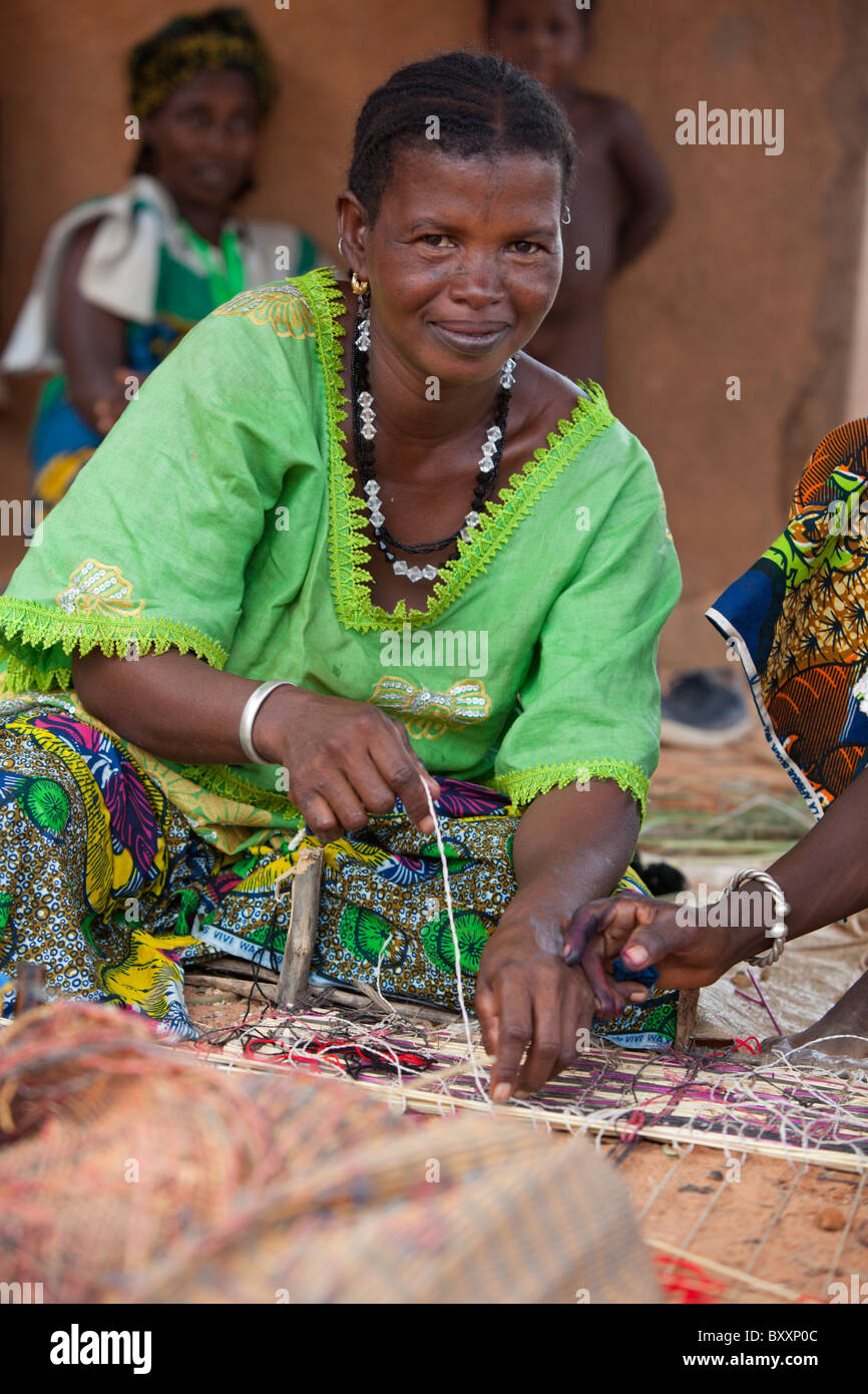 In the town of Djibo in northern Burkina Faso, a Fulani woman weaves a straw mat. Stock Photo