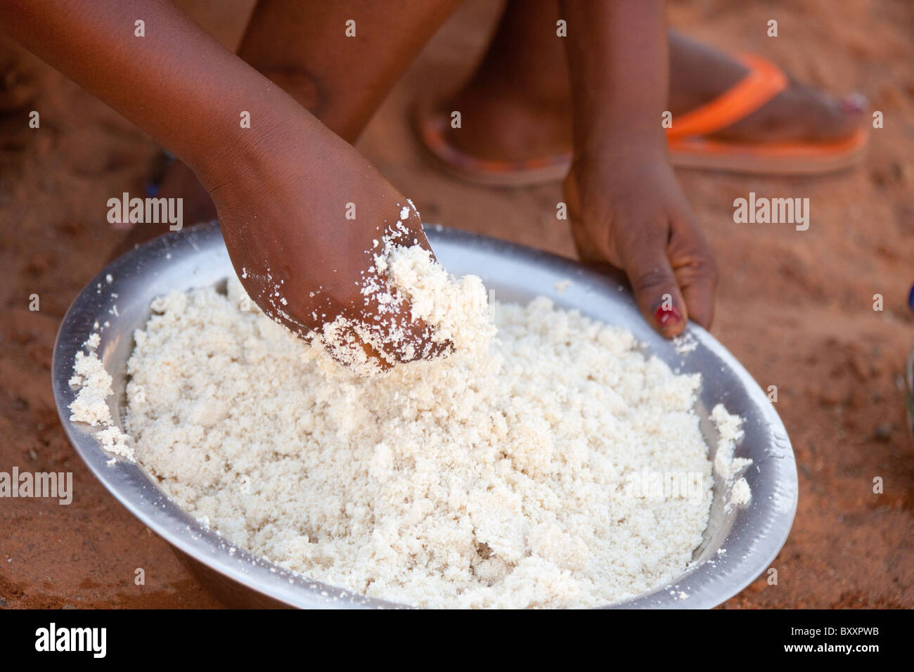 A Fulani woman in the town of Djibo in northern Burkina Faso kneads manioc flour, which she will use to make couscous (attieke). Stock Photo
