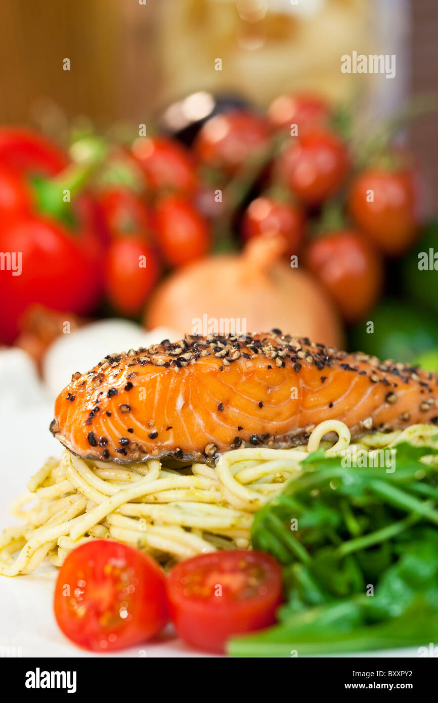 Peppered salmon fillet with spaghetti pasta tomatoes and green salad