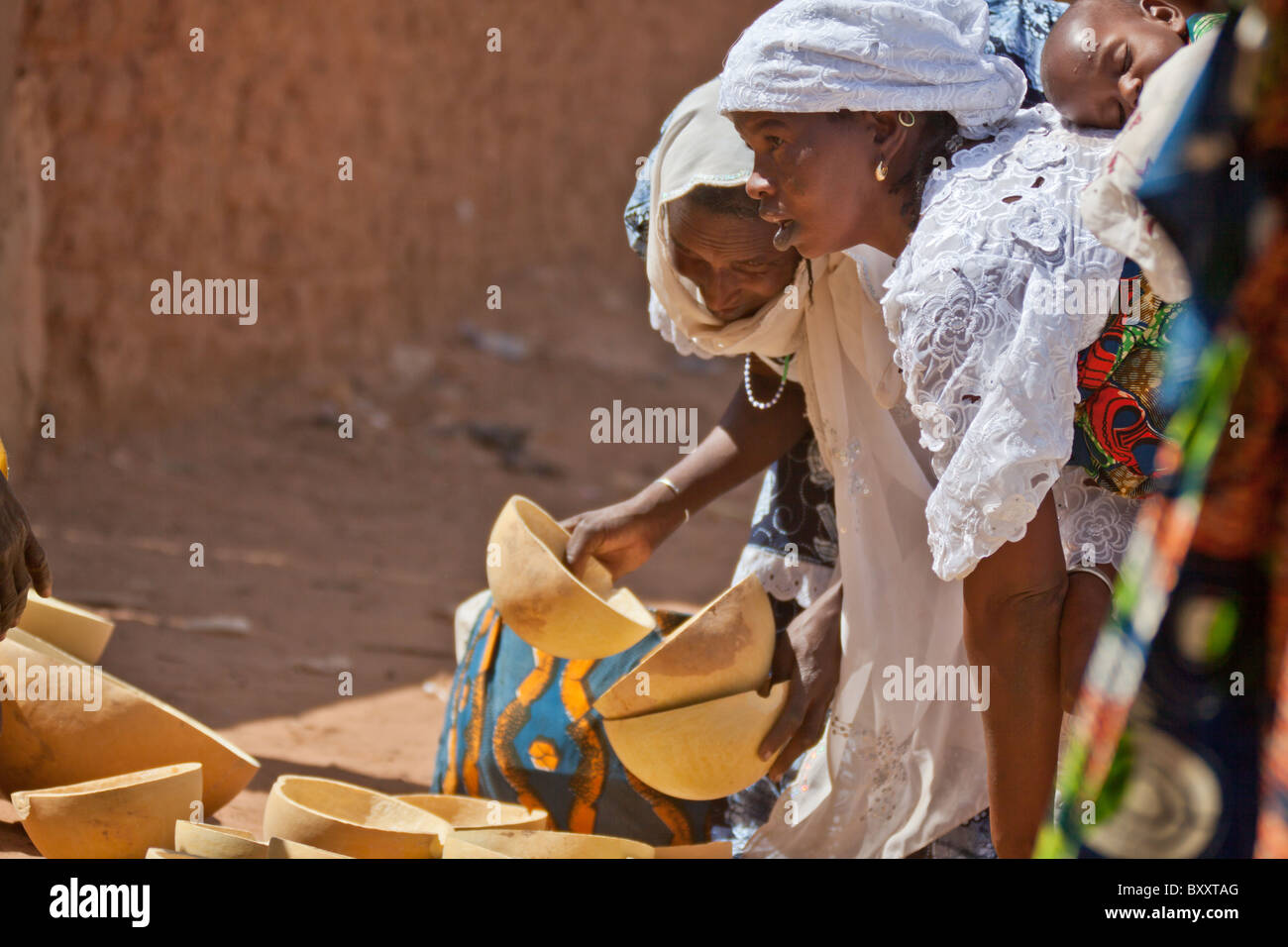 Two Fulani women inspect the calabashes for sale in the weekly market of Djibo in northern Burkina Faso. Stock Photo
