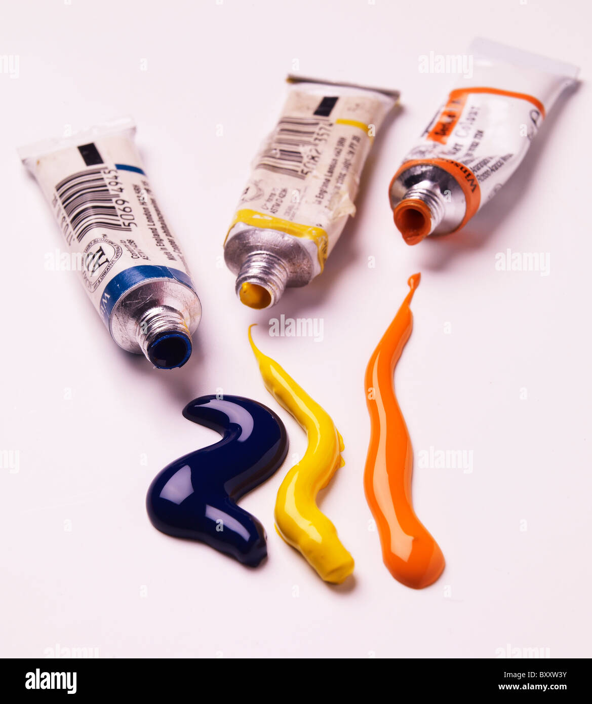 3 three tube of colured colored paint with squirts of paint coming out of them Stock Photo