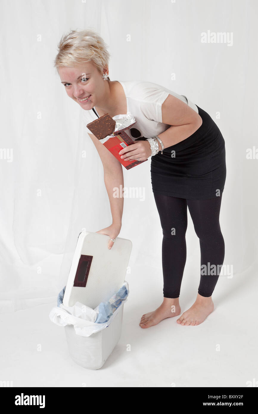A young blond woman no longer willing to take the strain of watching her weight. Chocolate tastes better without stress. Stock Photo