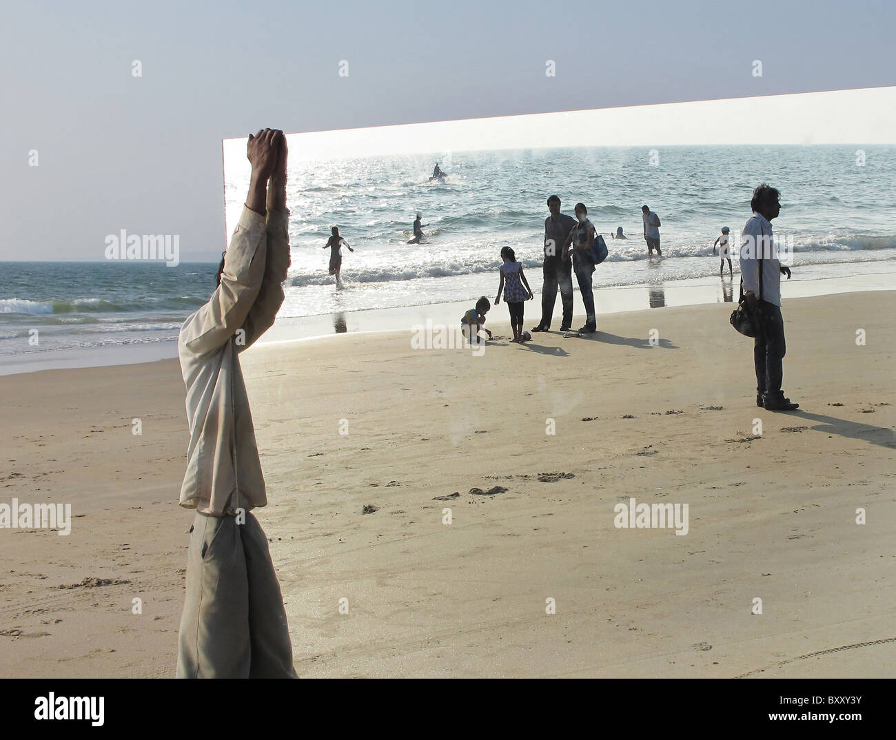 A worker guards a giant mirror on Majorda Beach, Goa, India which was being readied for the production of a Bollywood Movie bein Stock Photo