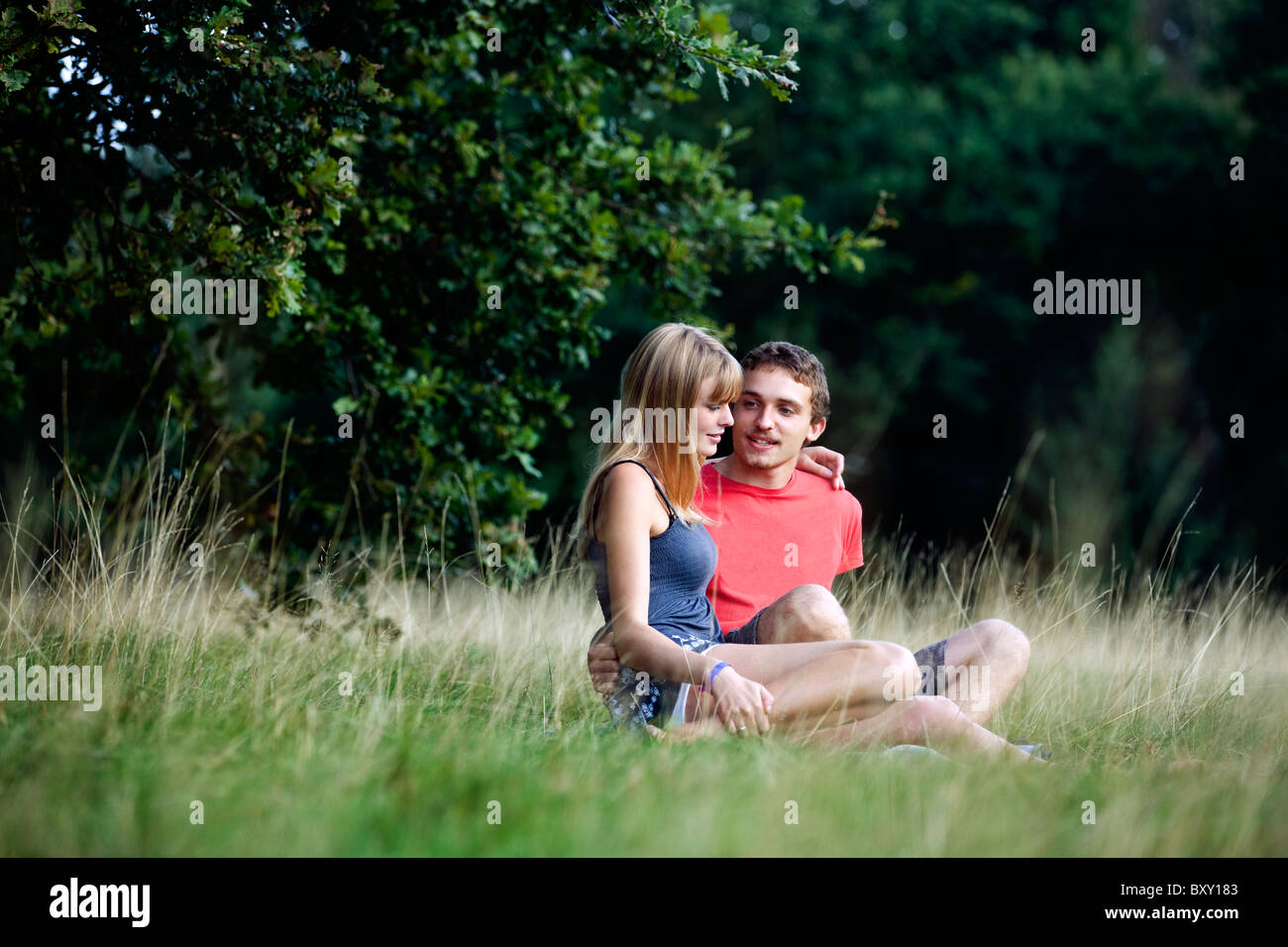 A young couple sitting on the grass Stock Photo - Alamy