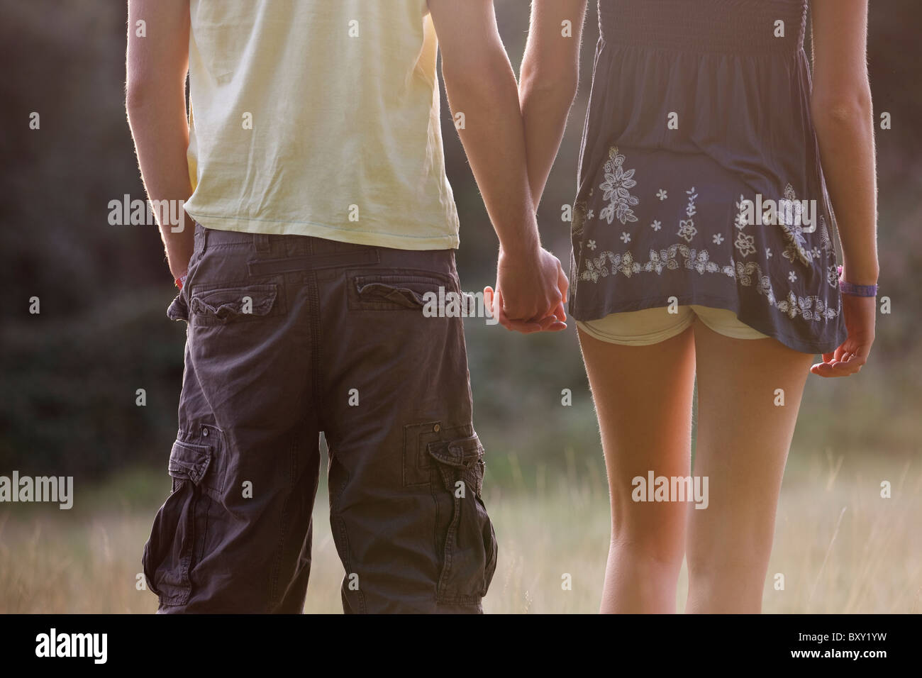 Rear view of a young couple outdoors, holding hands Stock Photo - Alamy