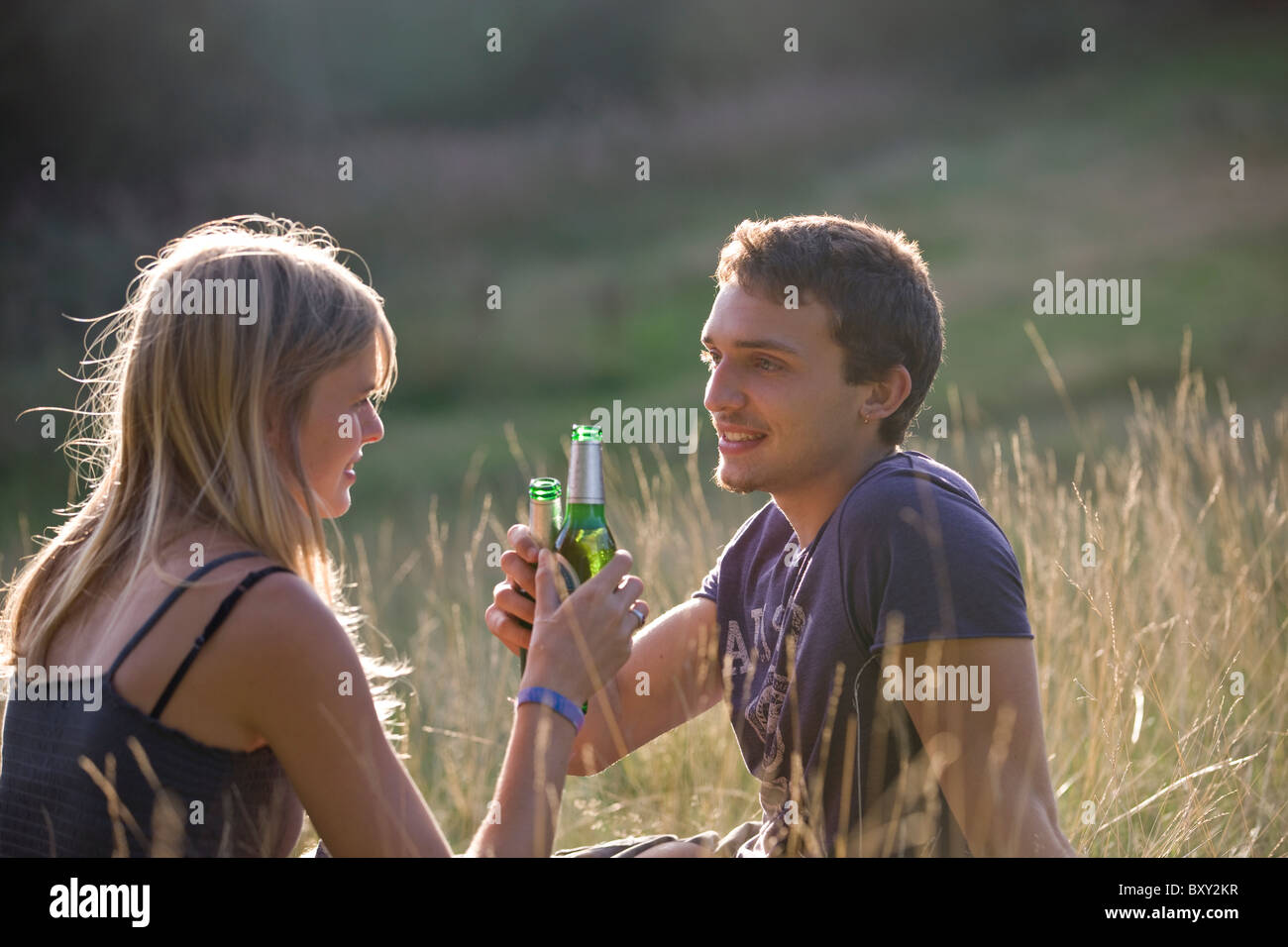 A Young Couple Sitting Outdoors Drinking Beer Stock Photo Alamy