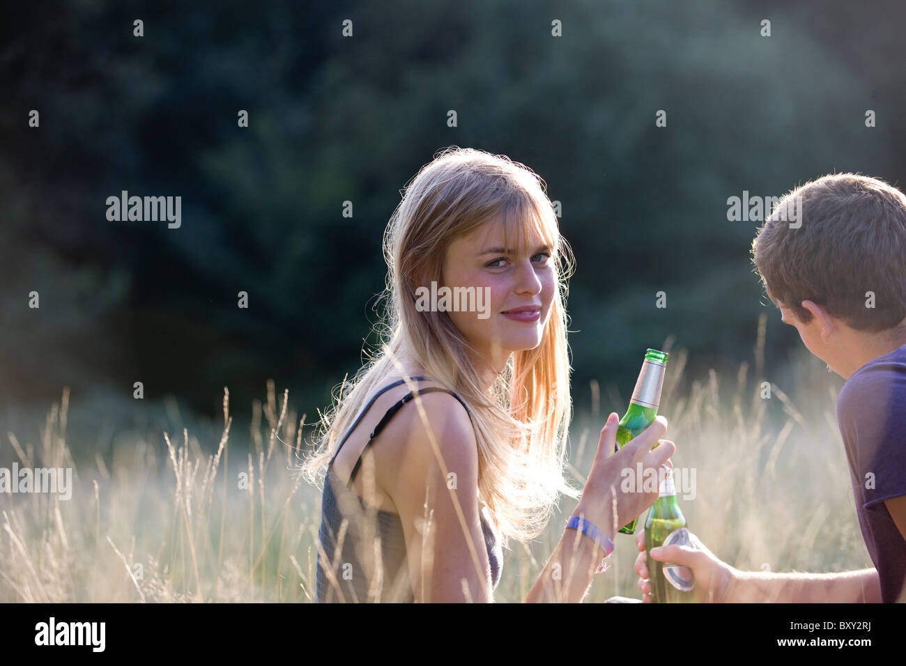 A young couple sitting outdoors, drinking beer Stock Photo