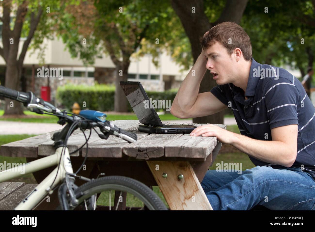 Twenty-something male student grimacing over what he sees on his computer screen Stock Photo