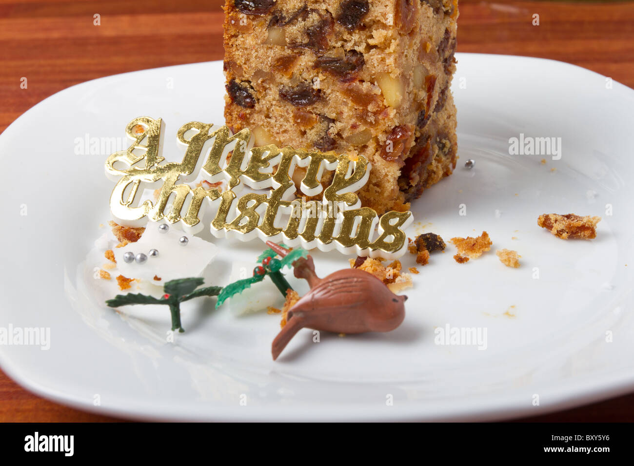 Last piece of christmas cake on plate with crumbs and decorations. Stock Photo