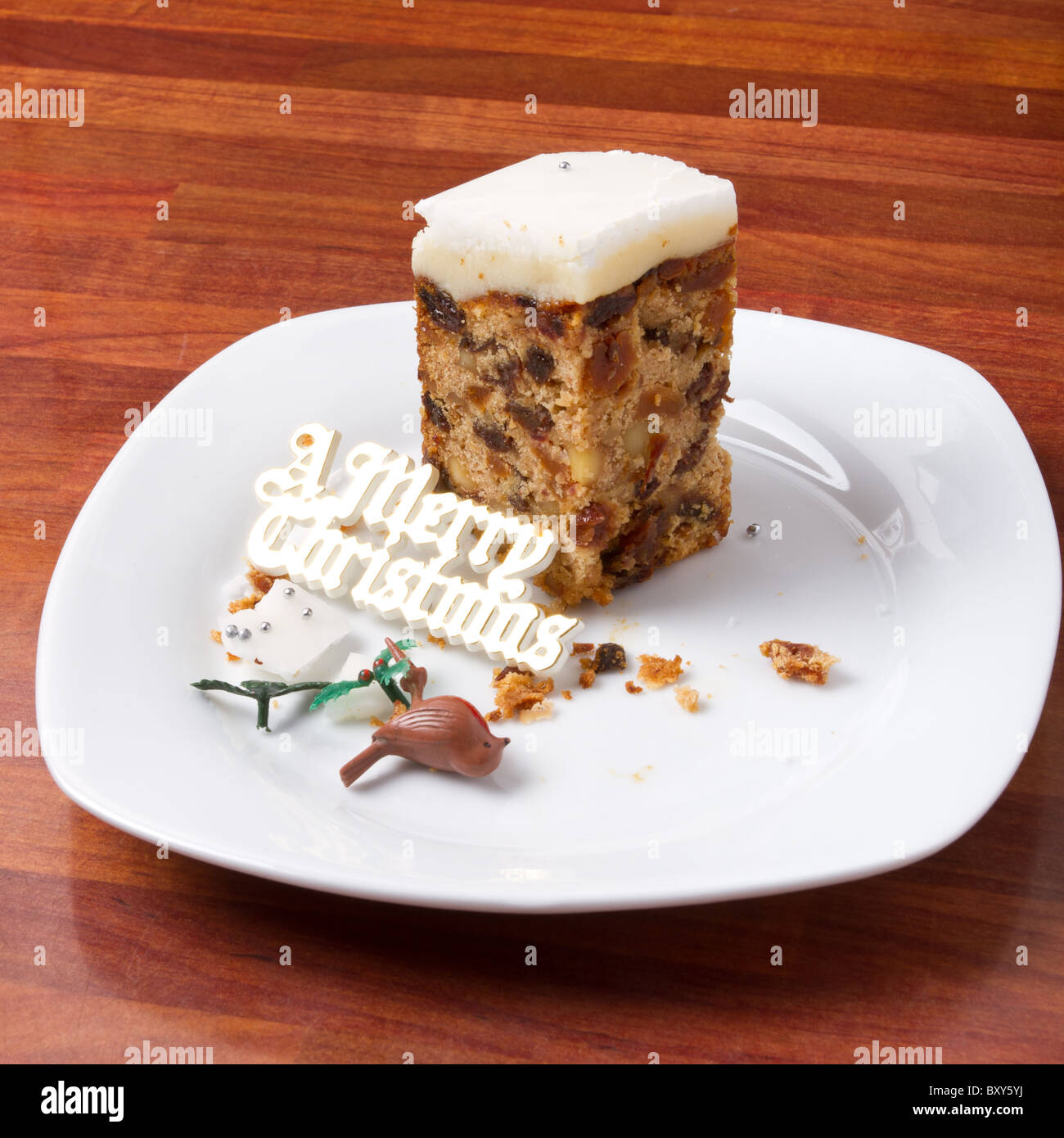 Last piece of christmas cake on plate with crumbs and decorations. Stock Photo