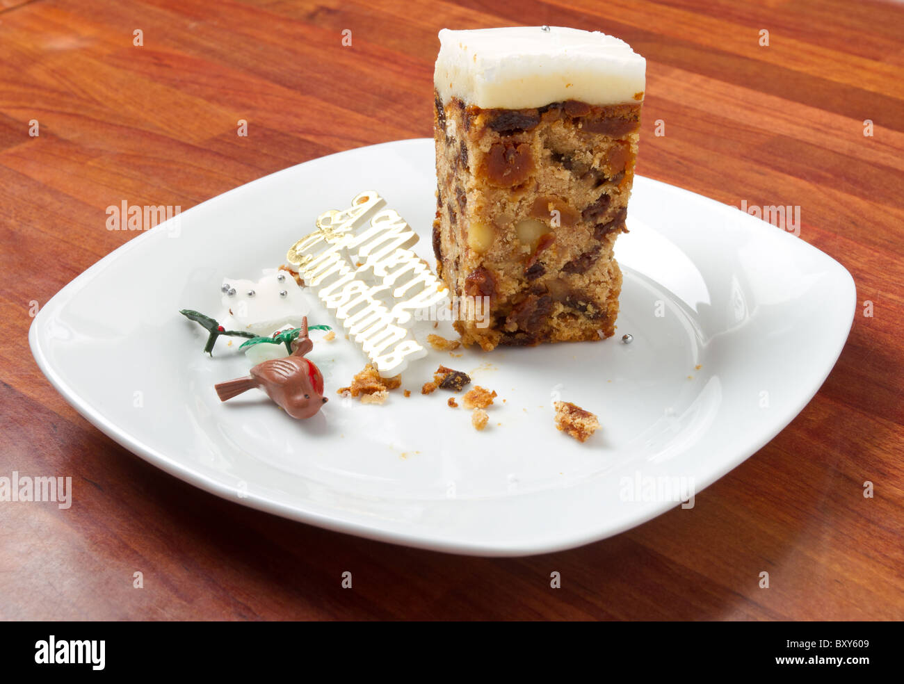 Last piece of Christmas cake on plate with crumbs and decorations. Stock Photo