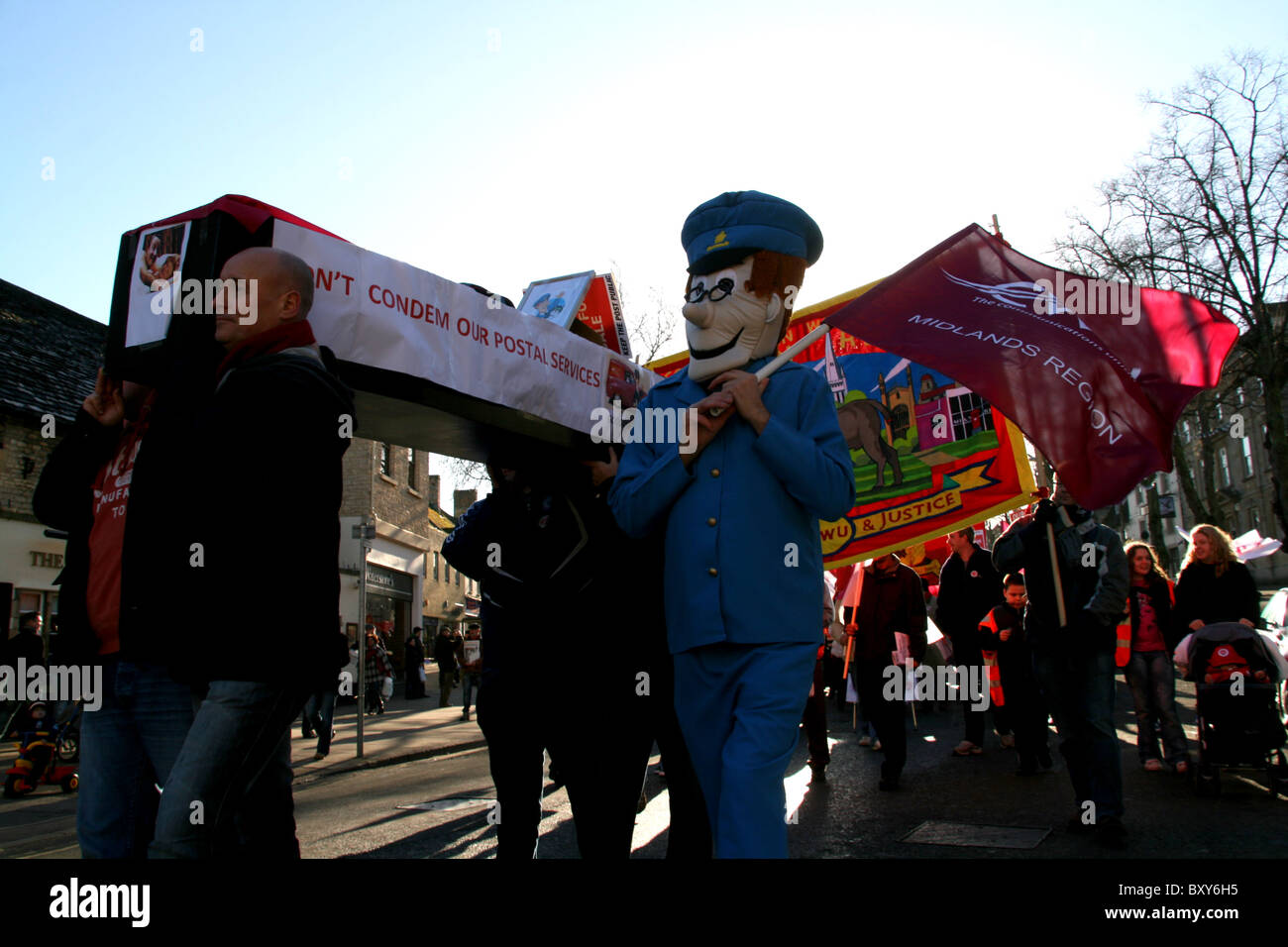 Coffin carried by protester and a protester dressed as Postman Pat at Witney england during the royal mail protest. Stock Photo