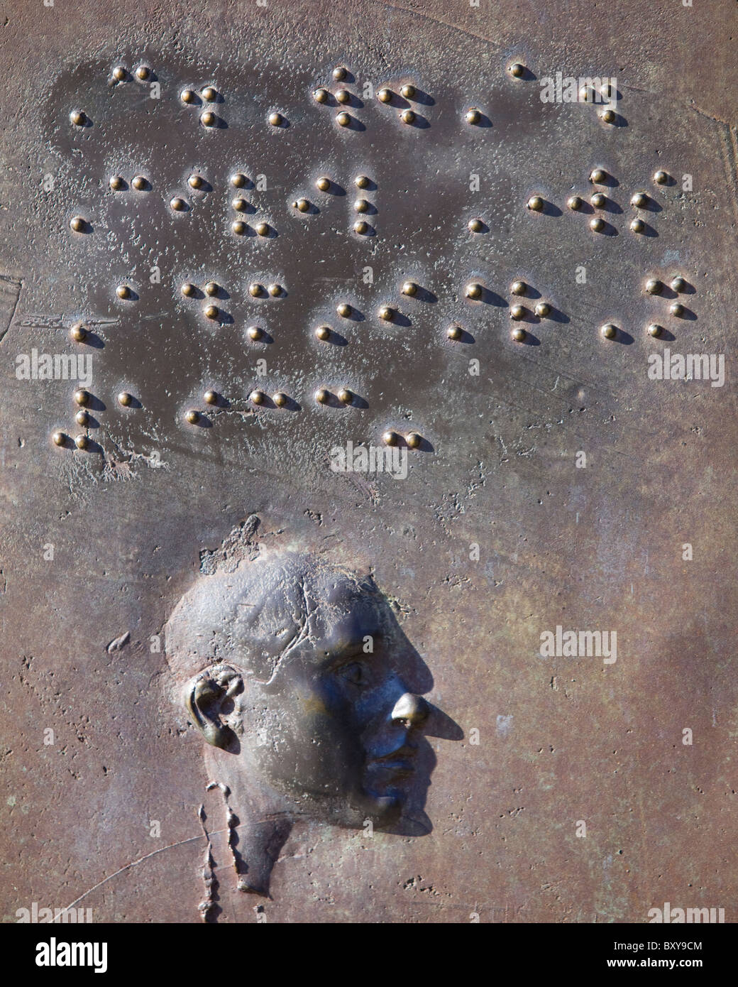 A bronze relief sculpture of braille text and a man's profile Stock Photo
