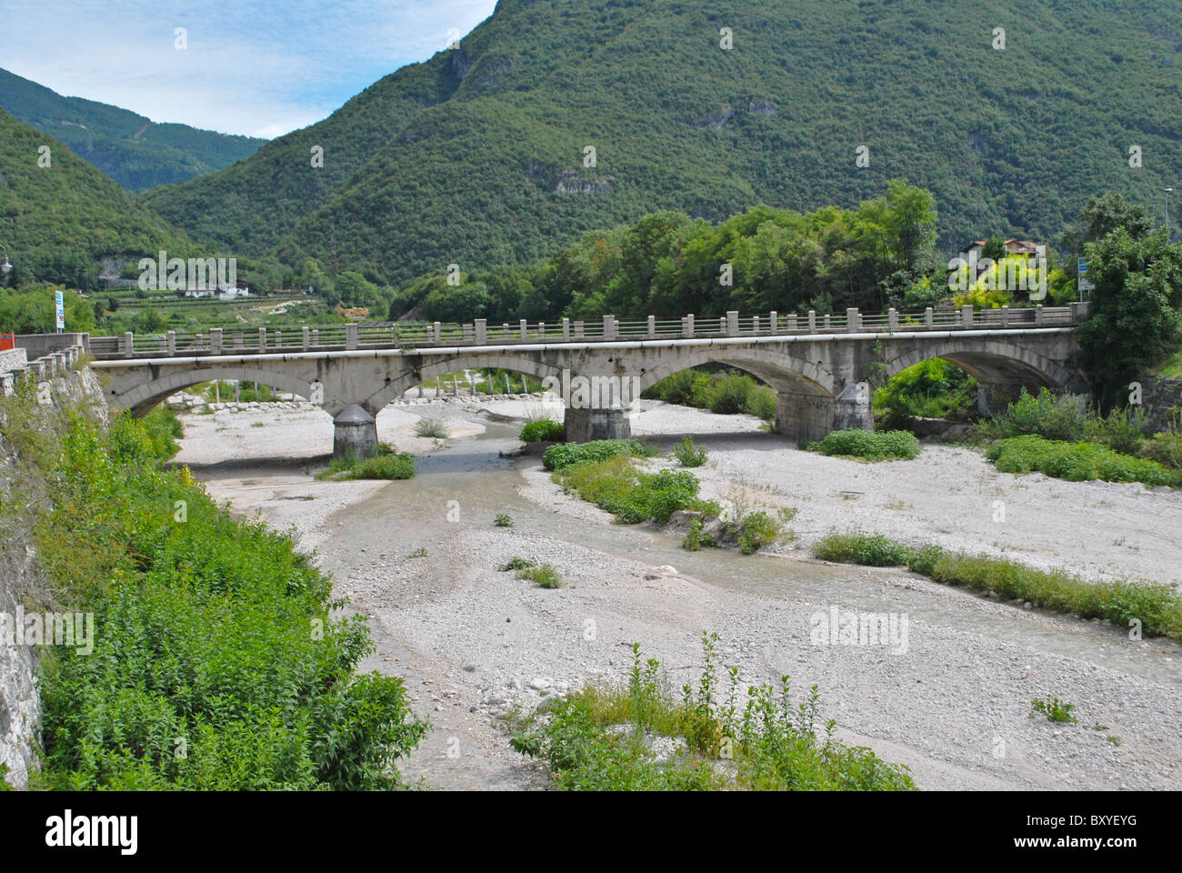 river of clear water with vegetation in the dry stream bed with bridge Stock Photo