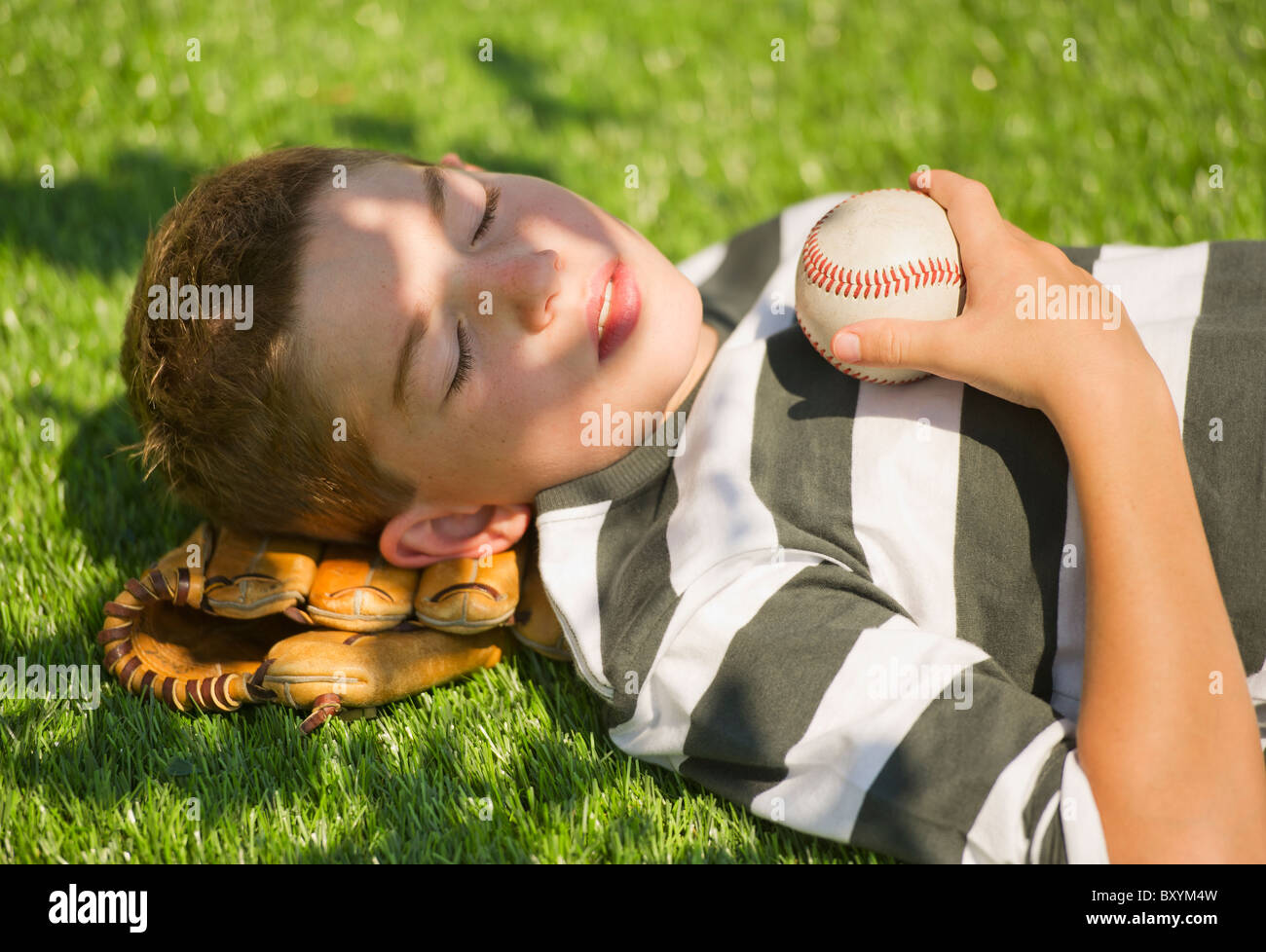 Boy holding baseball and baseball glove lying on grass Stock Photo Alamy