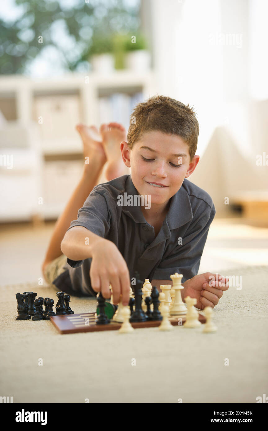 Boy lying on floor and playing chess Stock Photo