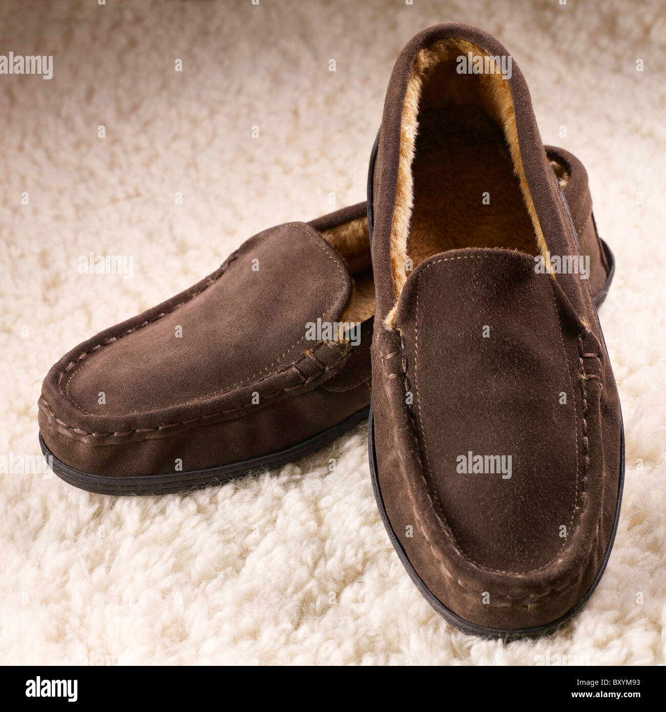 a pair of mens brown slippers shoes on a sheepskin fleece background Stock Photo