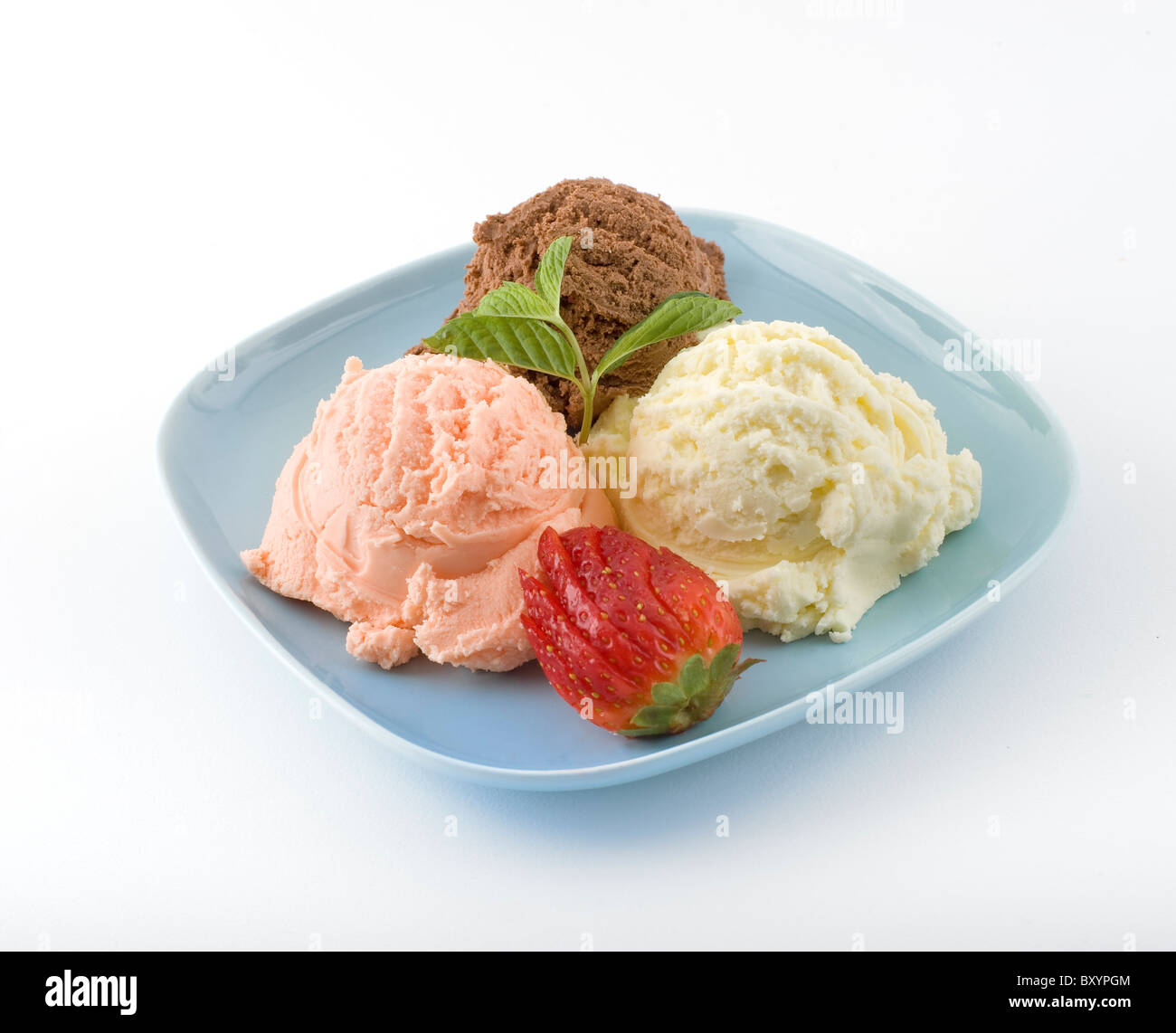 three flavored ice cream scoops on a pale blue plate, with