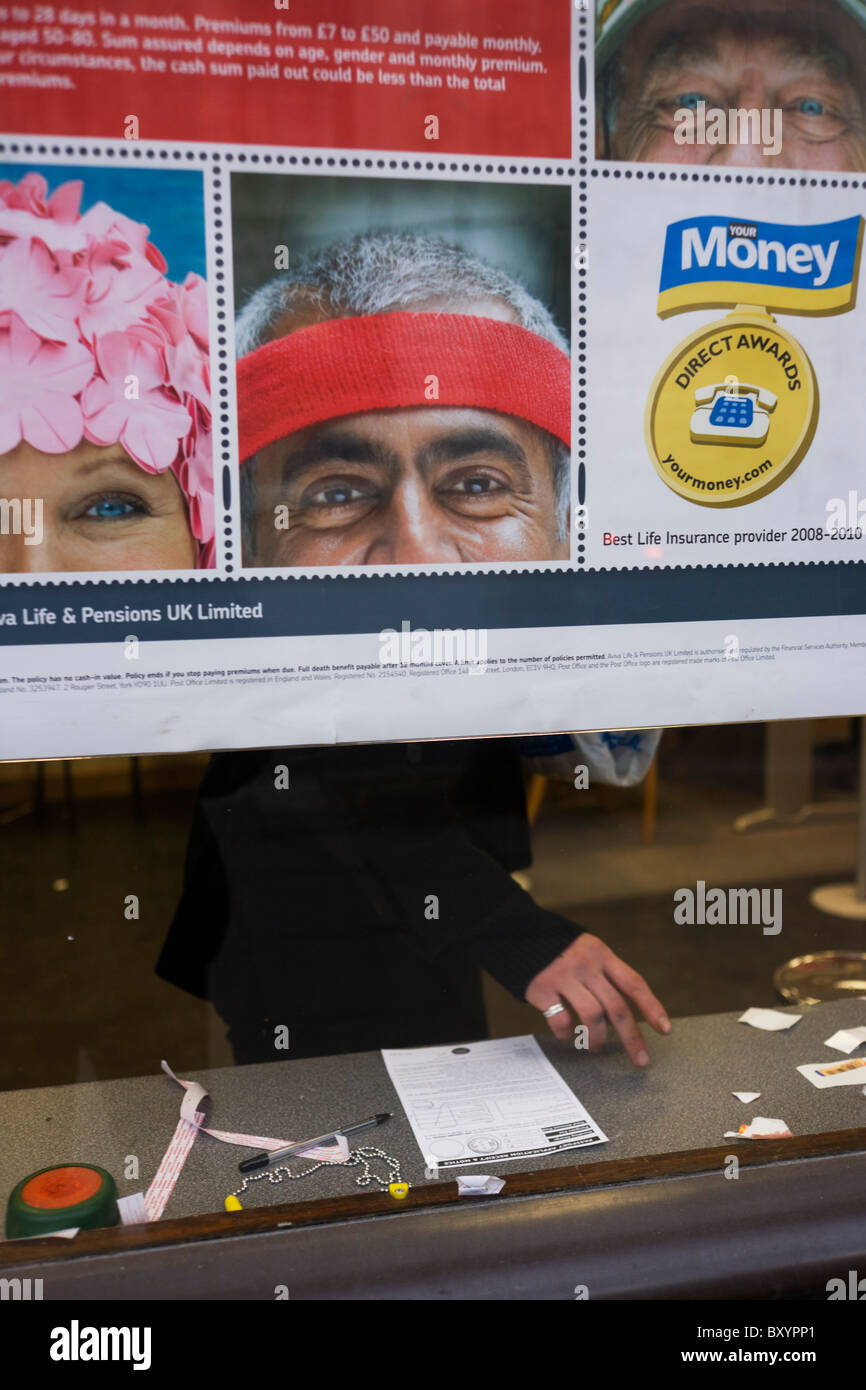 The hands and fingers of an anonymous customer seen through a city Post Office window, behind a