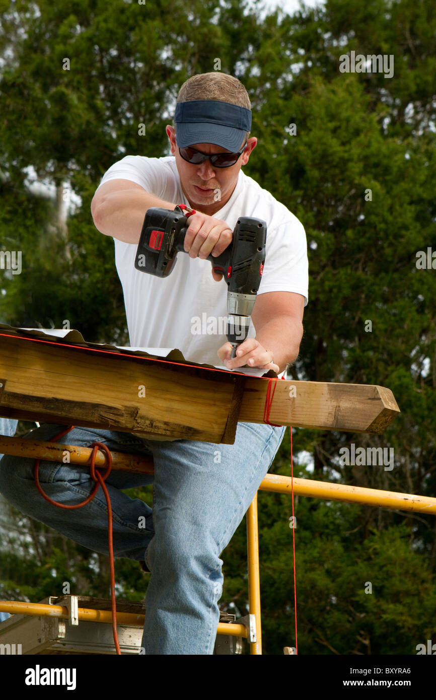 Construction worker uses a battery powered drill to attach corrugated
