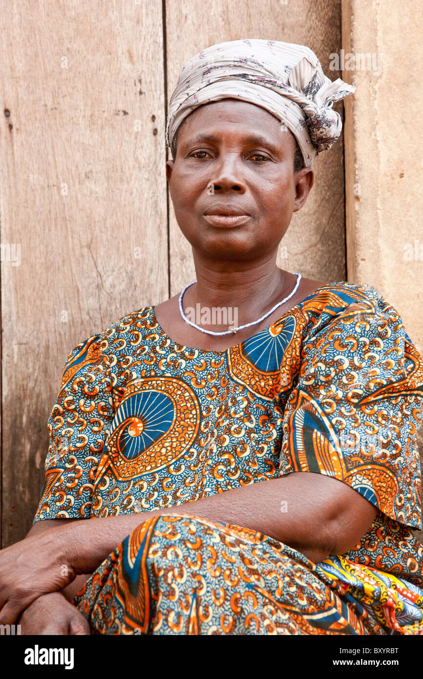 A woman whose village participated in a community empowerment project sits in front of her home. Stock Photo