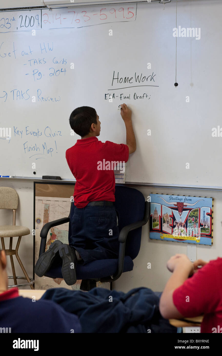 Hispanic male student writes homework assignment on whiteboard in class at Peak Preparatory Academy public charter high school Stock Photo