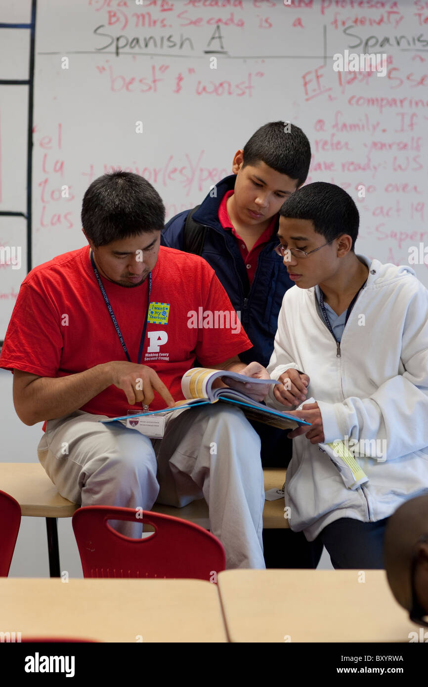 Spanish teacher (red shirt) works with male students after class at Peak Preparatory Academy, a public charter school in Dallas Stock Photo
