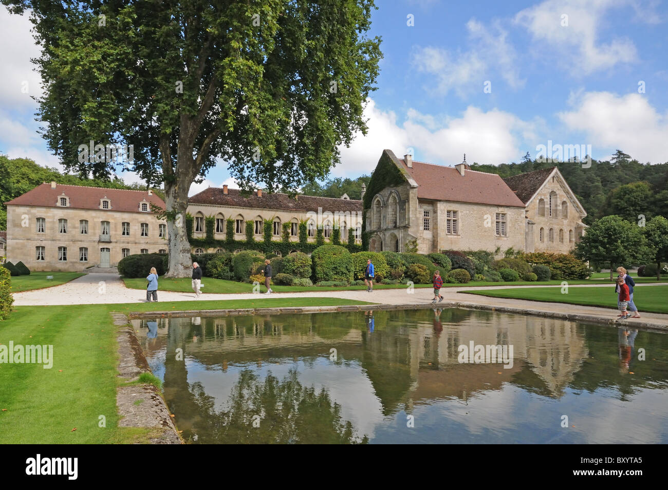 Abbot’s Lodging Refectory and Chapel with pool reflections and tourists at the Abbaye de Fontenay Burgundy France Stock Photo