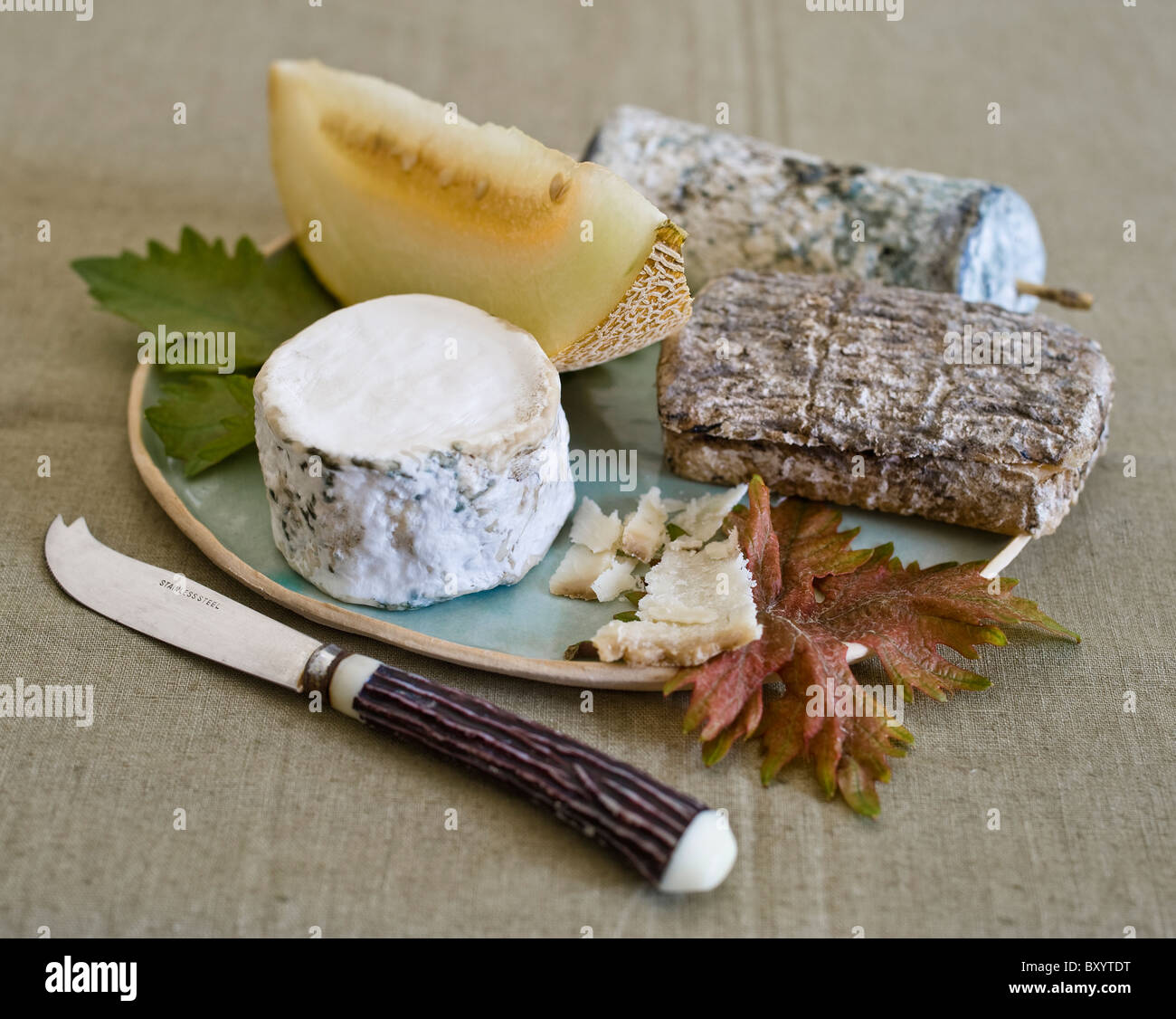 three goat cheeses with melon on plate with a cheese knife Stock Photo