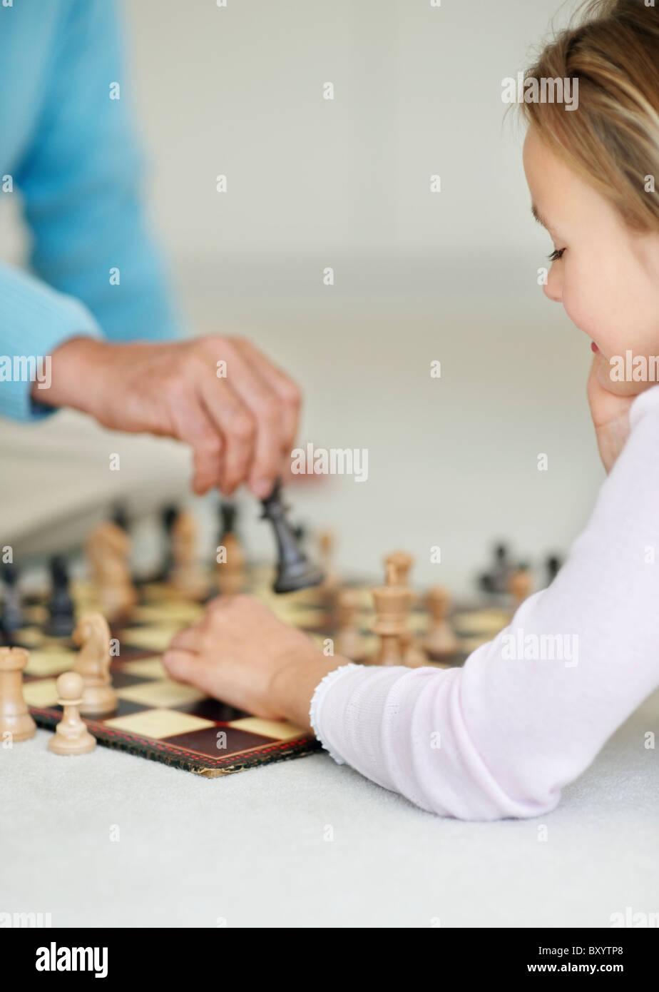 Granddaughter playing chess with grandfather Stock Photo