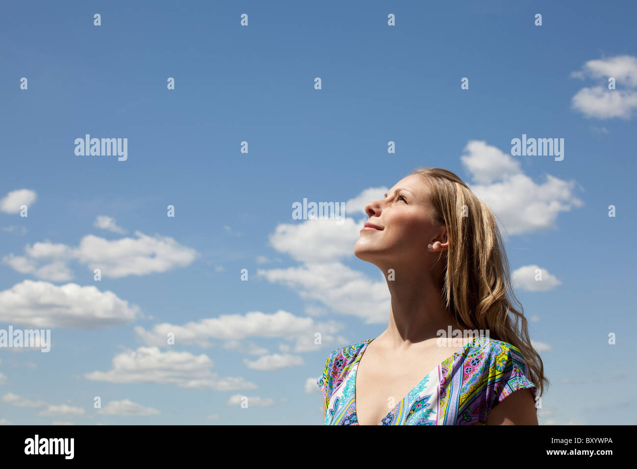 Young woman smiling against cloudy sky Stock Photo