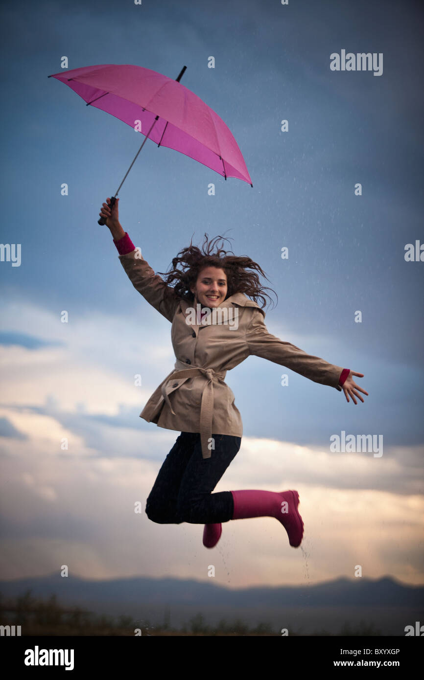 Young woman with umbrella under overcast sky Stock Photo