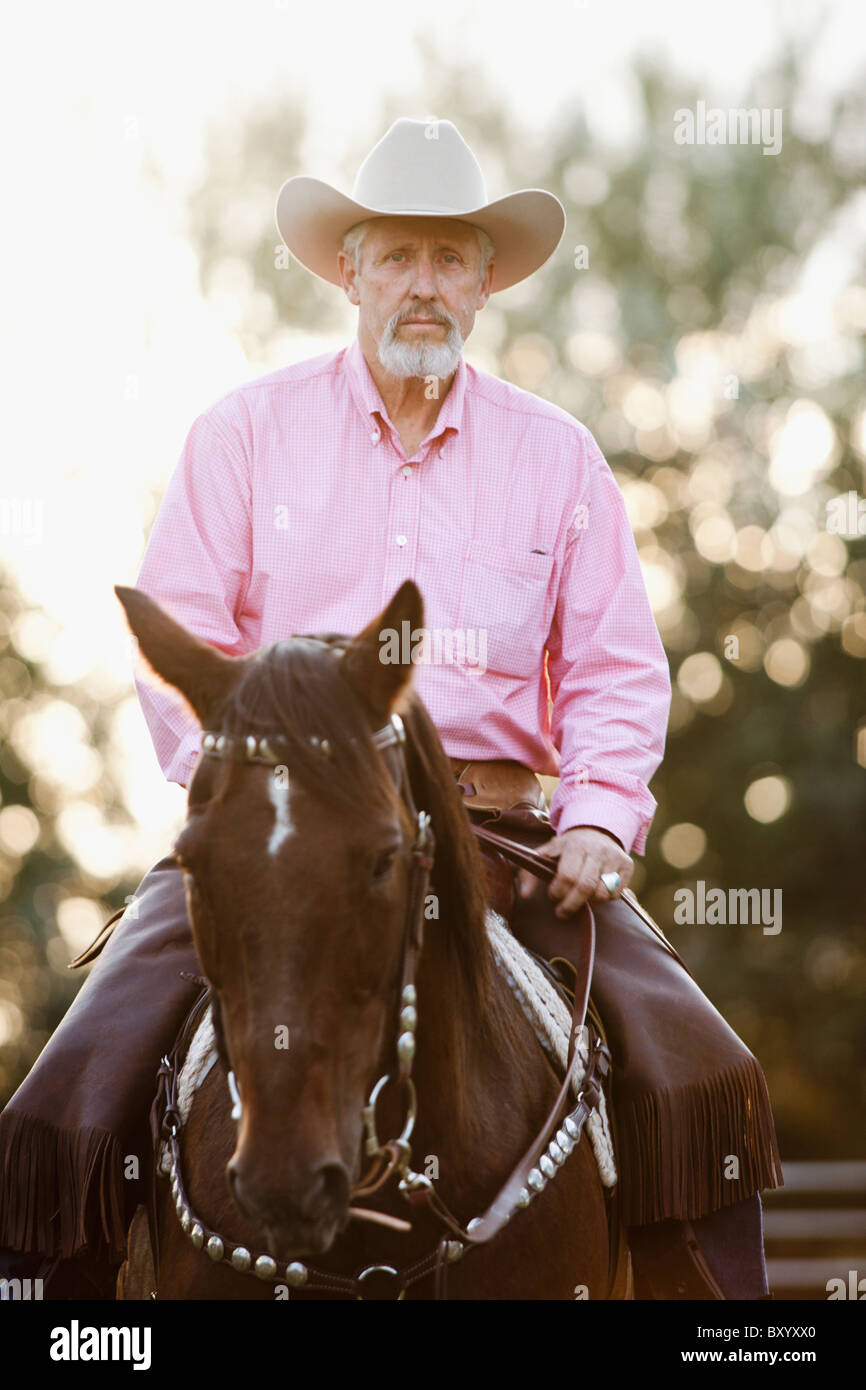 Portrait of senior man horseback riding in ranch Stock Photo
