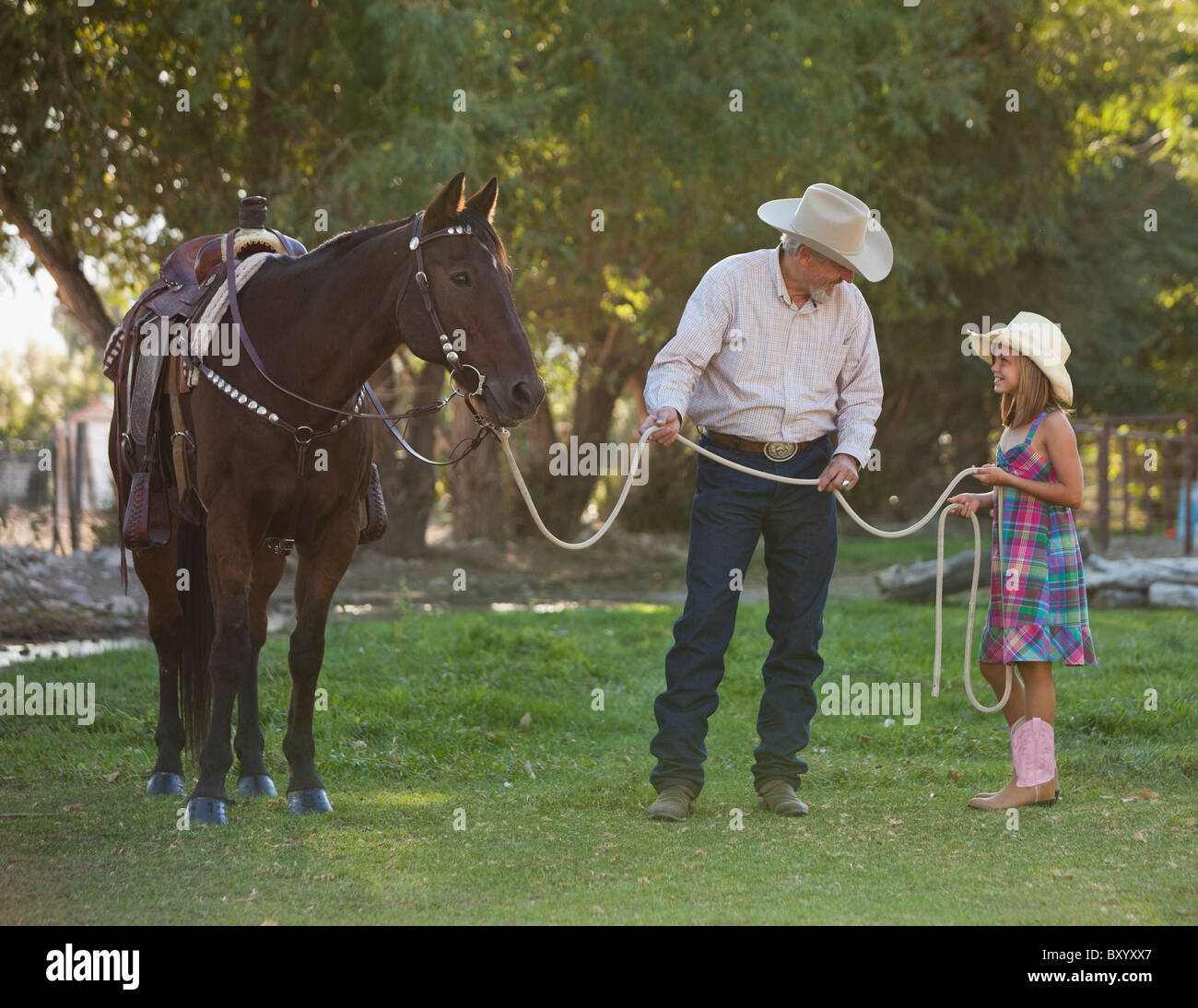 Senior man with granddaughter training horse in ranch Stock Photo