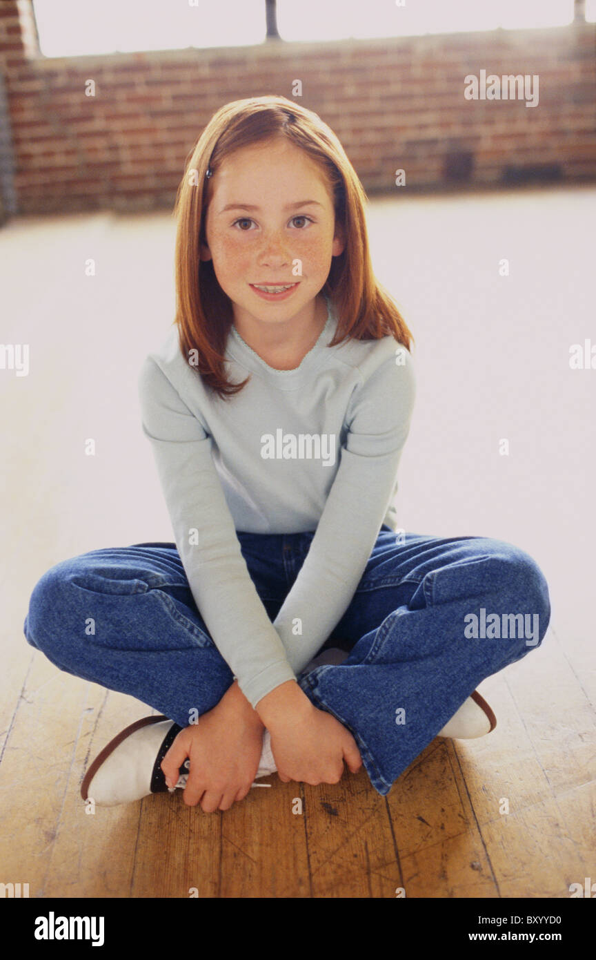 Cute young girl sitting cross legged Stock Photo - Alamy