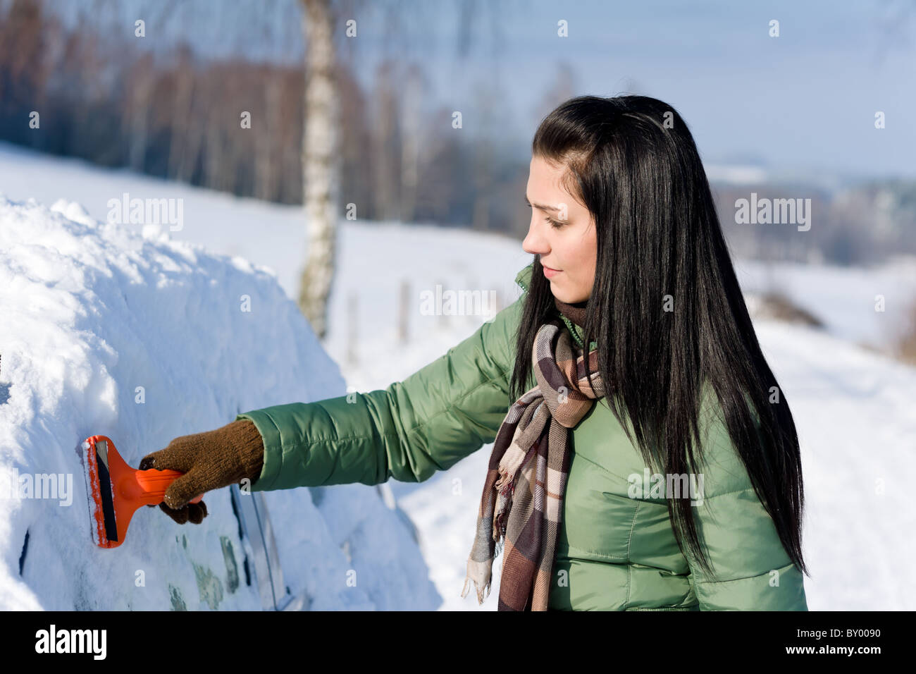 Winter car - woman remove snow from windshield with ice scraper Stock Photo