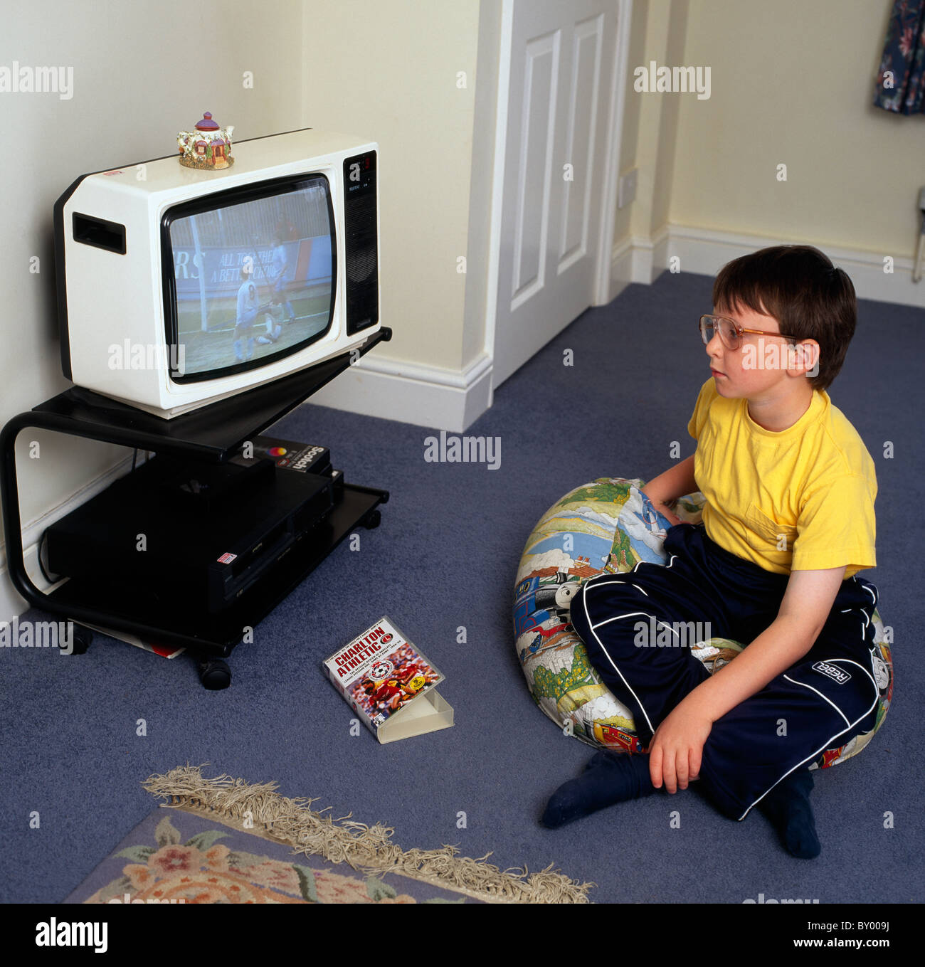 Young child at home watching the television in England in Great Britain in the United Kingdom. Childhood Children Life Lifestyle Stock Photo