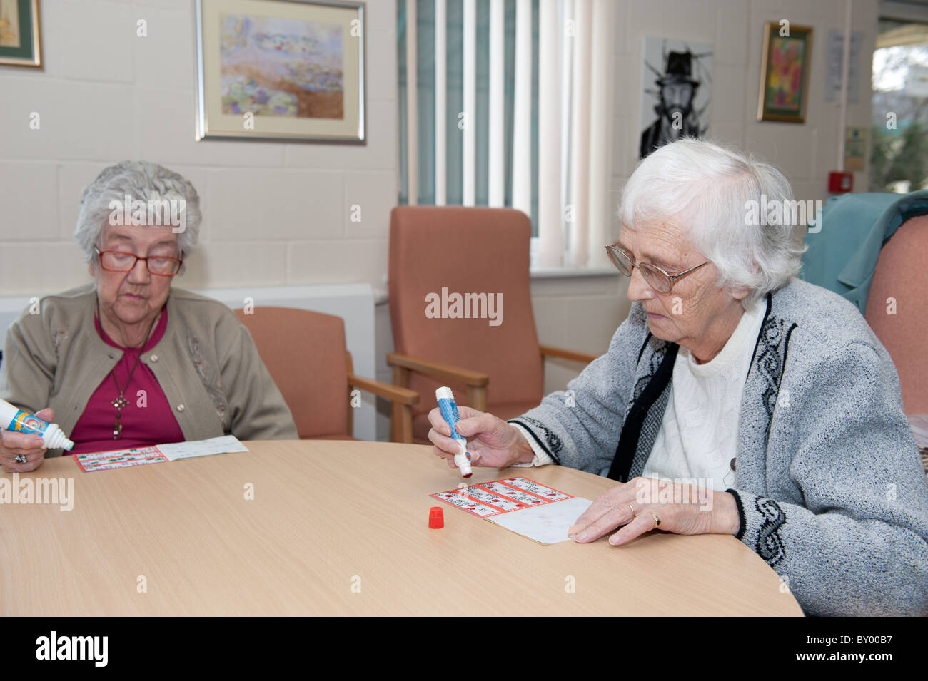 Two elderly ladies sitting at a table playing bingo in UK council run day centre. Stock Photo