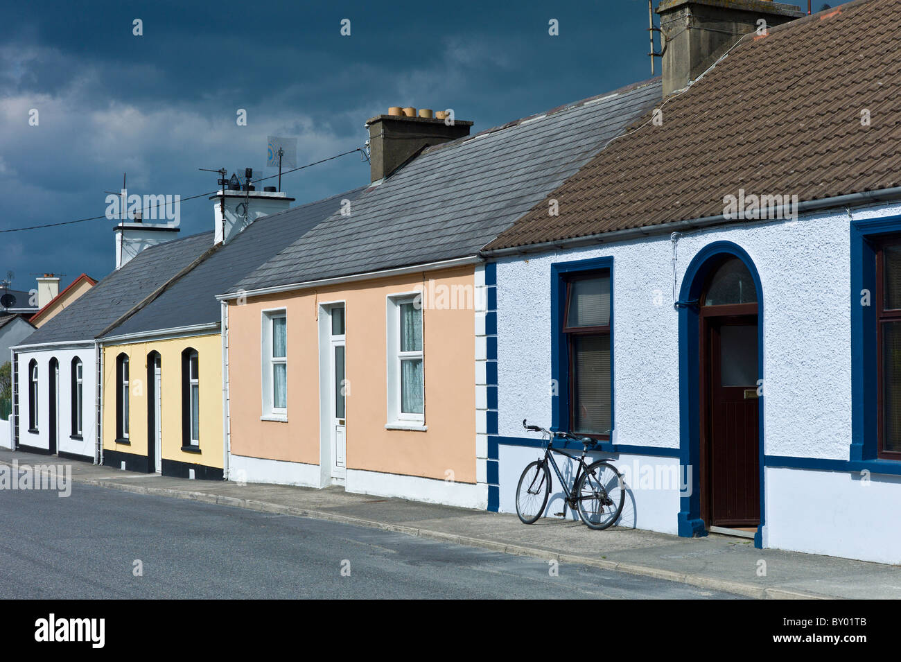 Street scene pastel painted terraced bungalows and bicycle in Railway Road, Kilkee, County Clare, West of Ireland Stock Photo