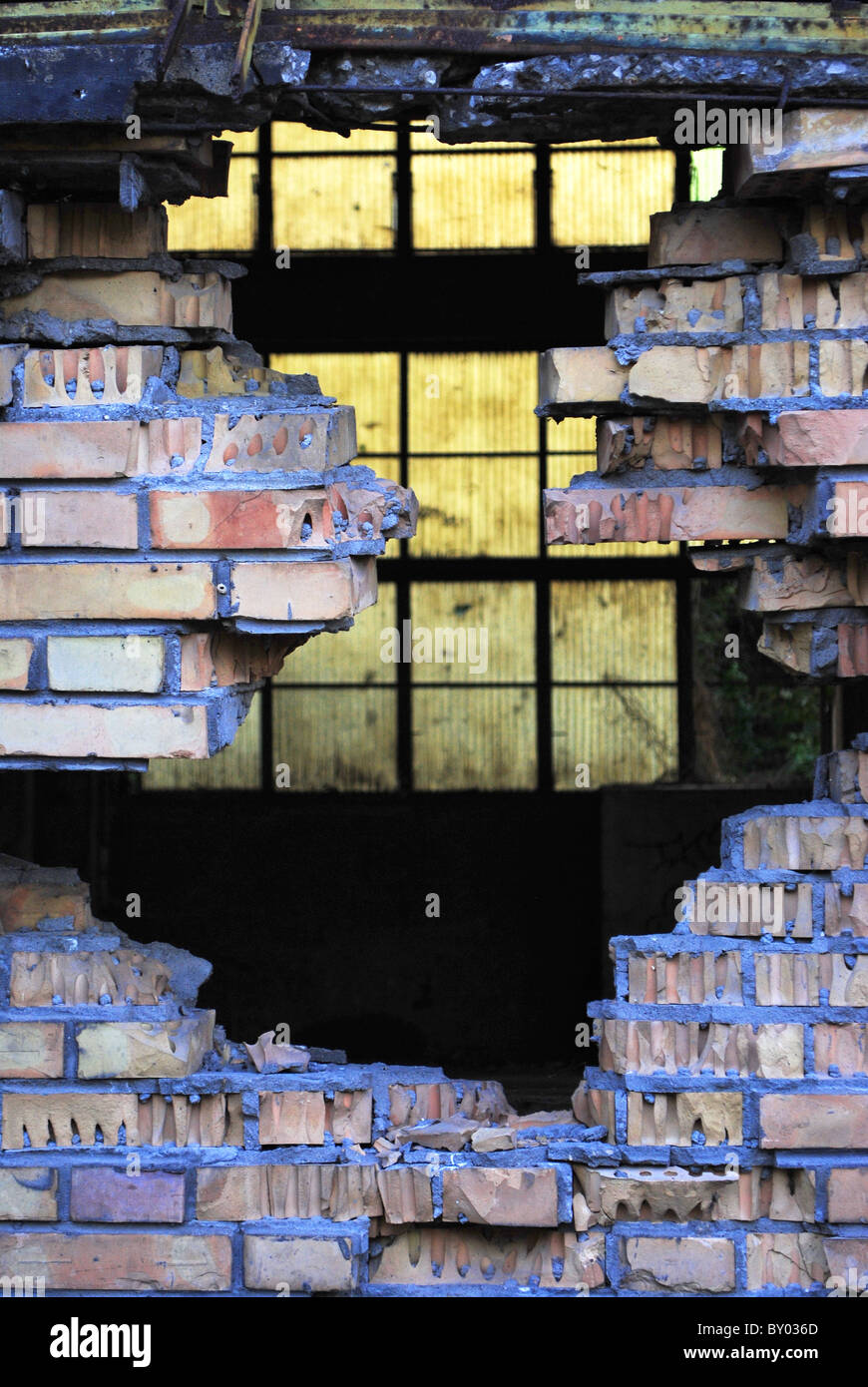 hole in the wall of red brick with concrete background blue plastic pellets Stock Photo
