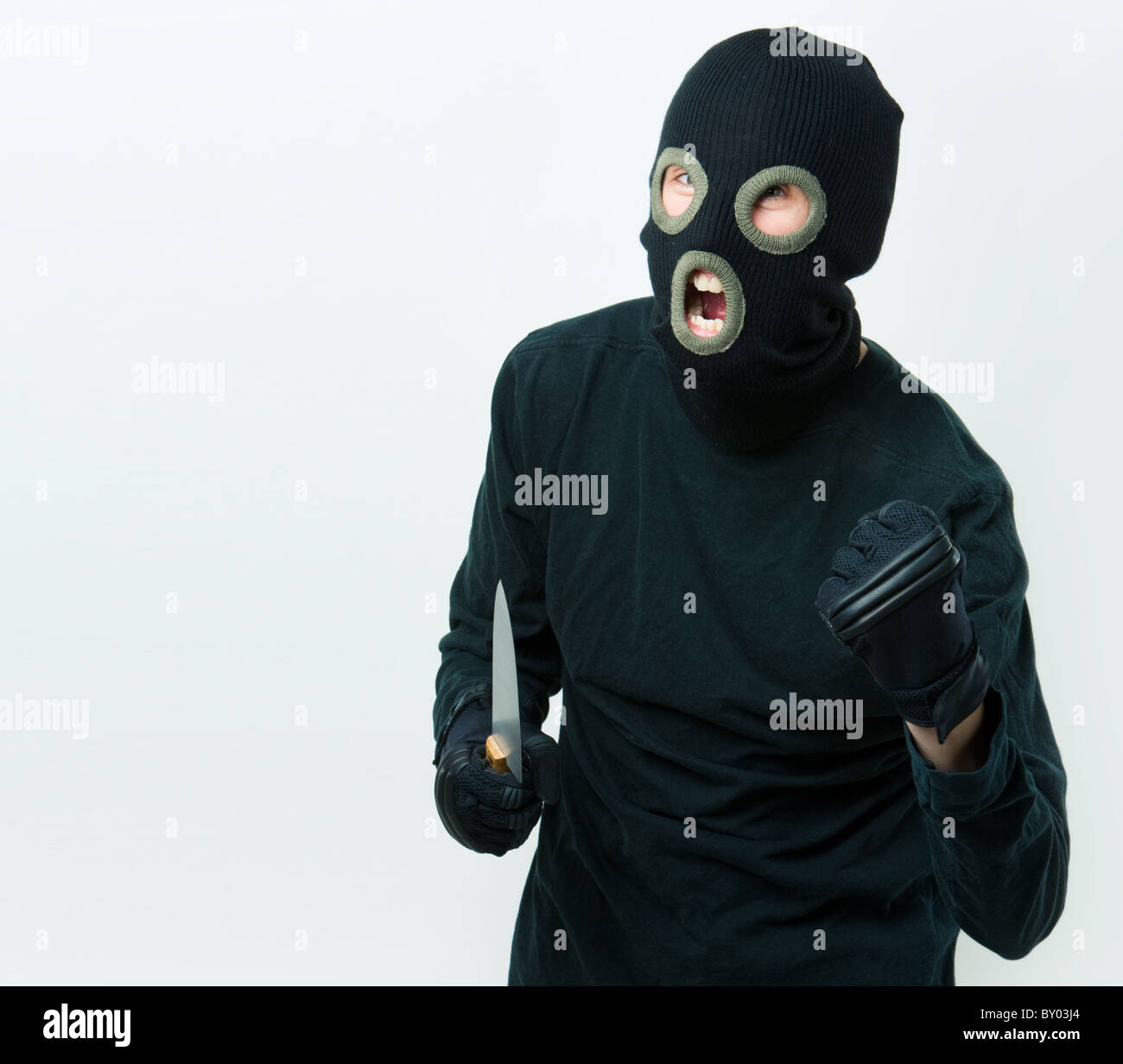 Portrait of felon in balaclava with knife in gloved hand Stock Photo