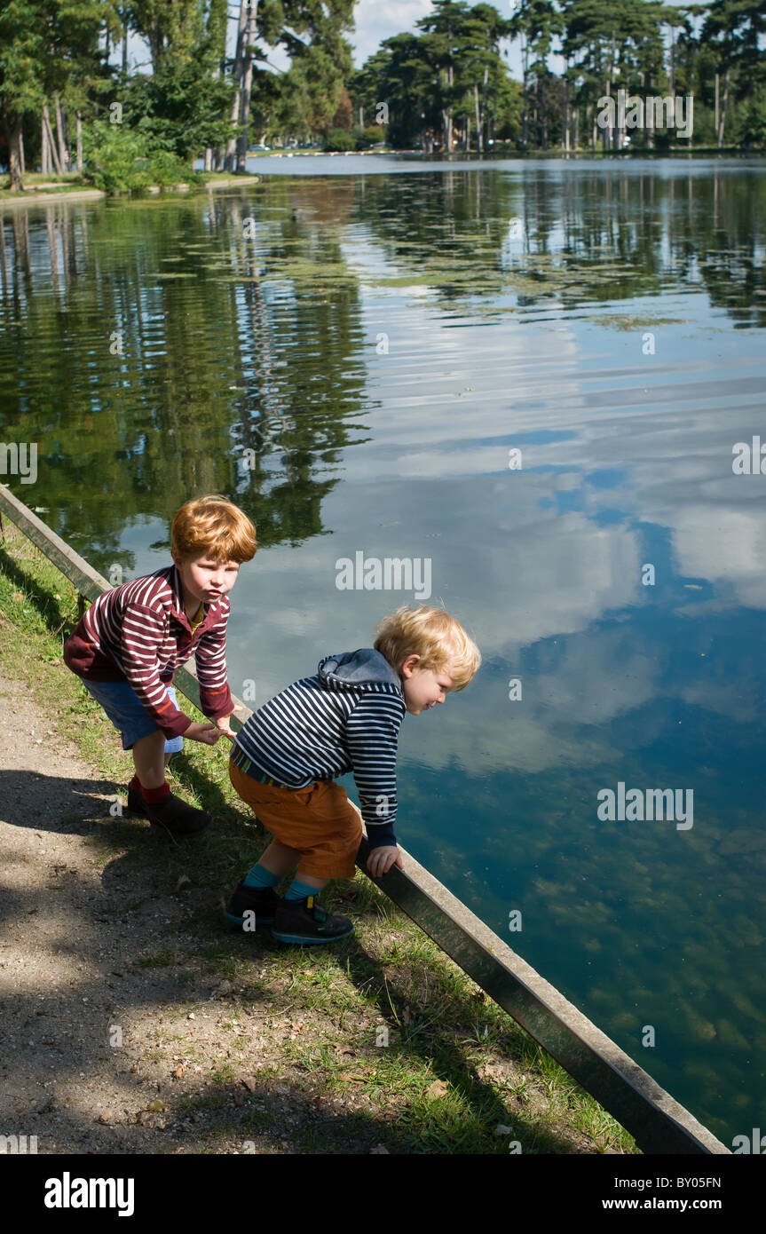 Two young boys playing by the side of a lake Stock Photo - Alamy