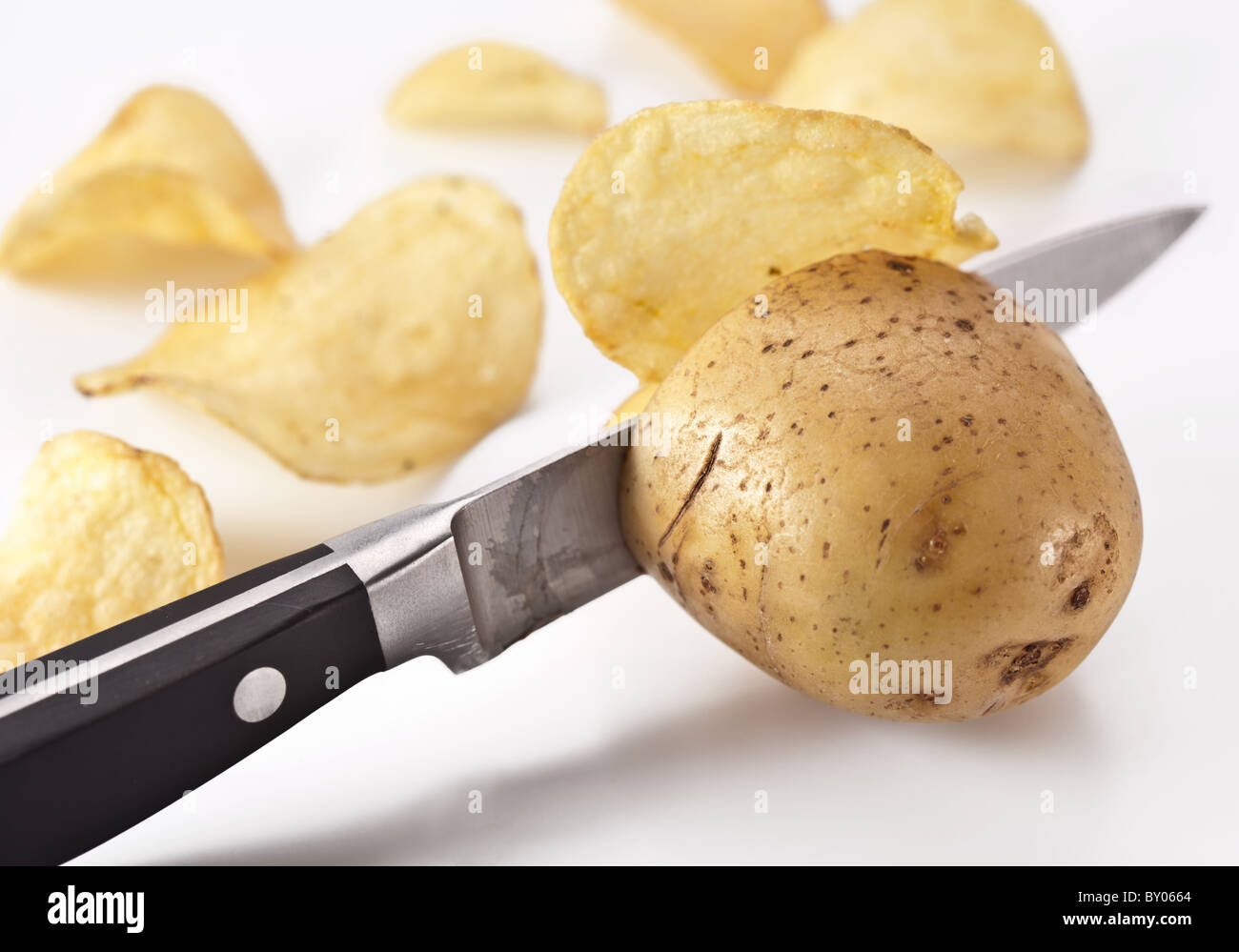 Conceptual image - the knife cuts fresh potatoes and potato chips are obtained. Stock Photo