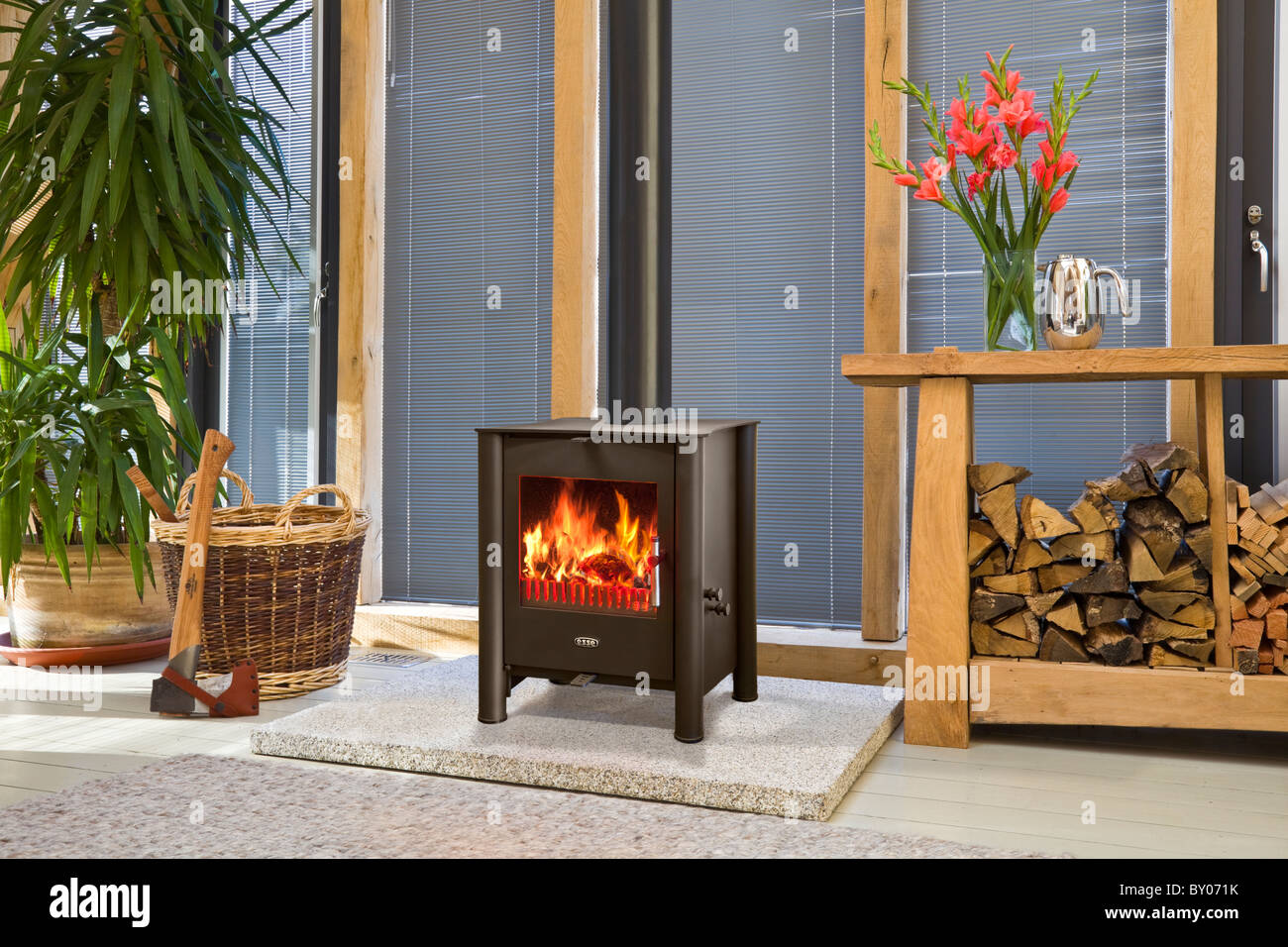 A wood burning stove in an oak framed building with log store Stock Photo