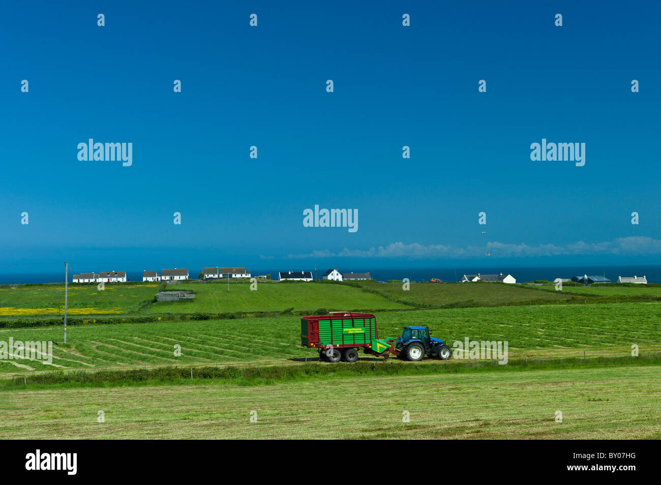Tractor and trailer at work in field near Doonbeg, County Clare, West of Ireland Stock Photo