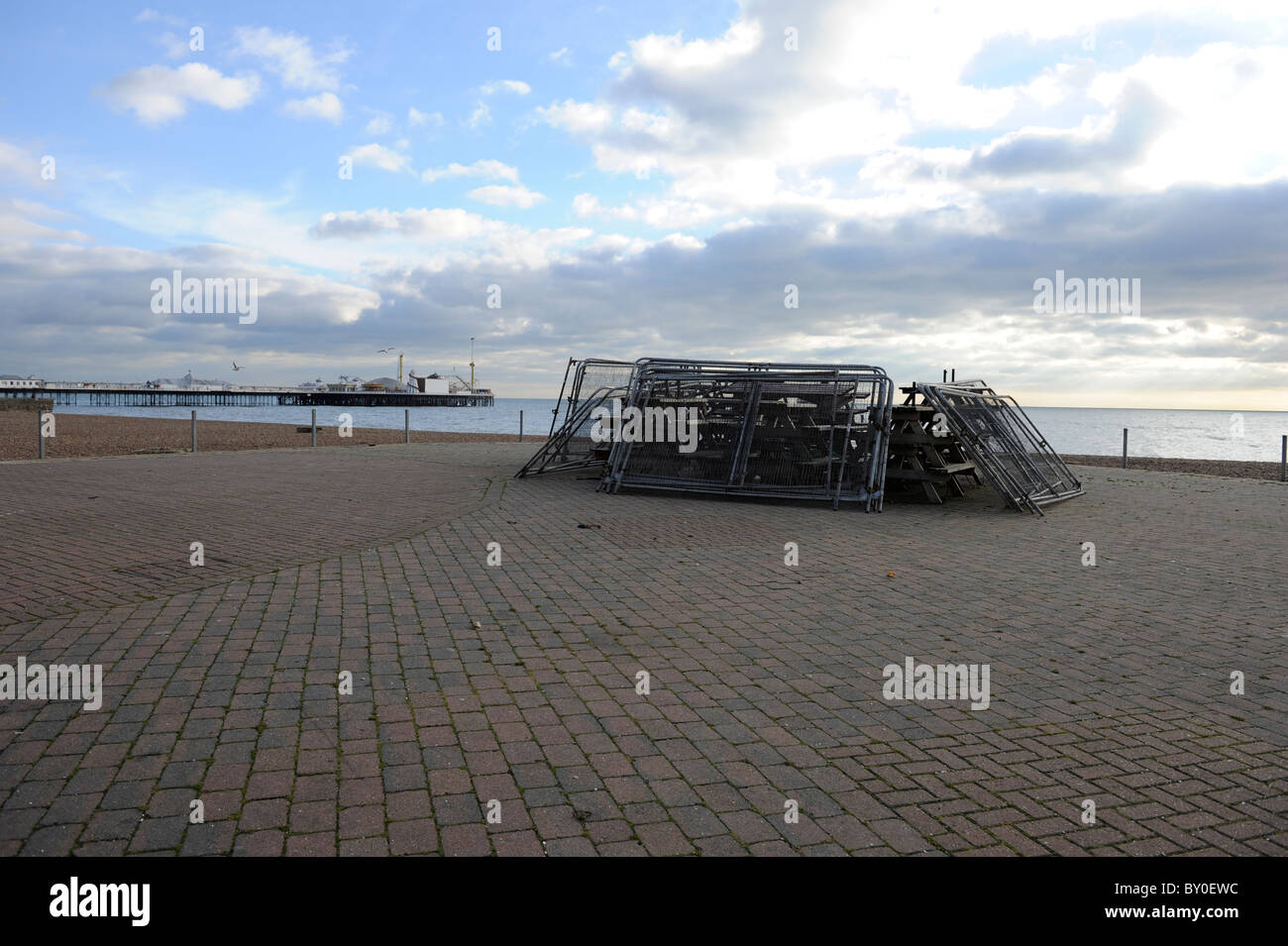 Tables piled up in winter outside cafe on Brighton sea front with Brighton Pier in background Stock Photo